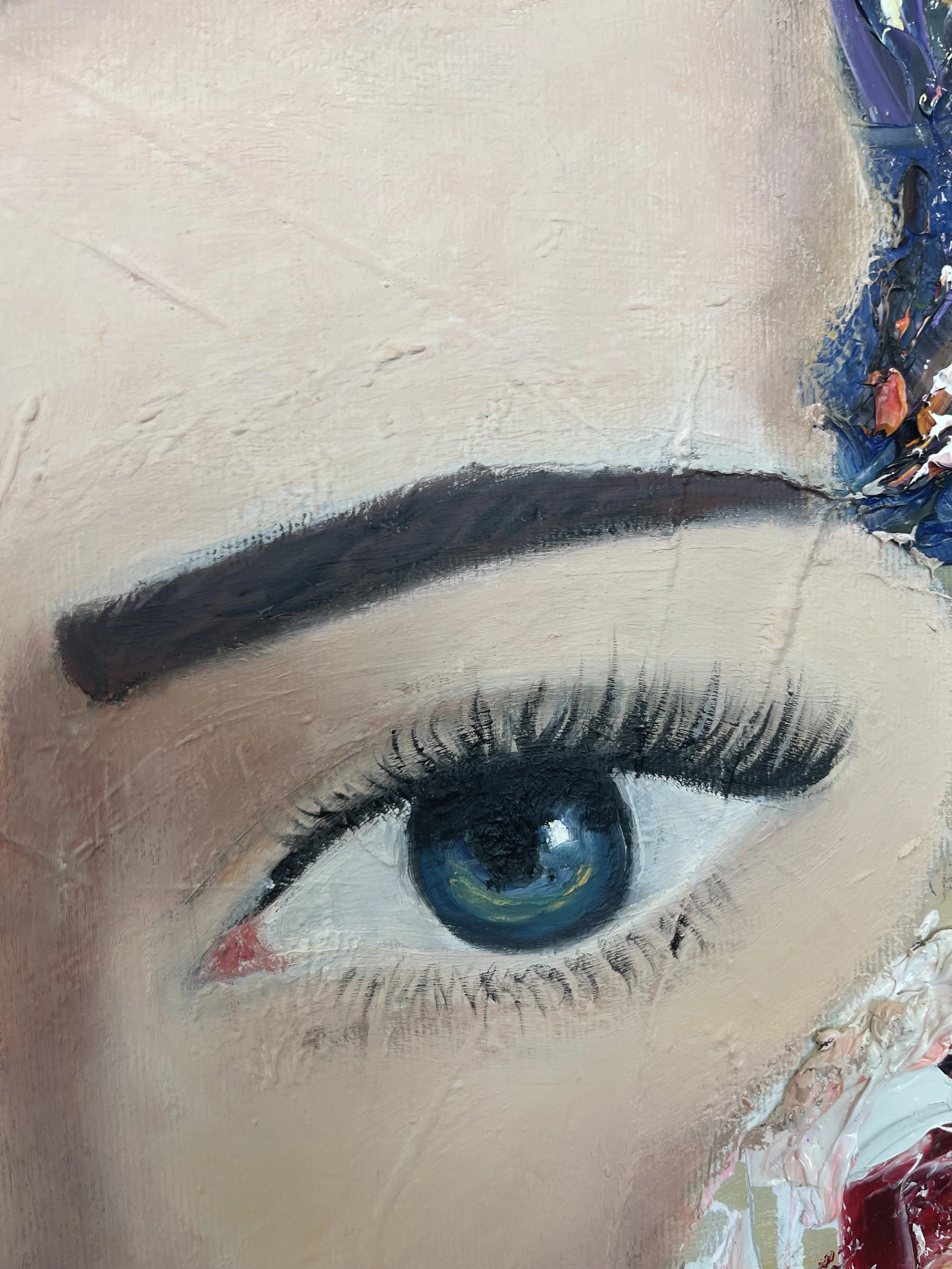 Close-up of a painted eye with a blue iris, dark eyebrows, and long eyelashes, on a textured canvas with color spots on the right side.