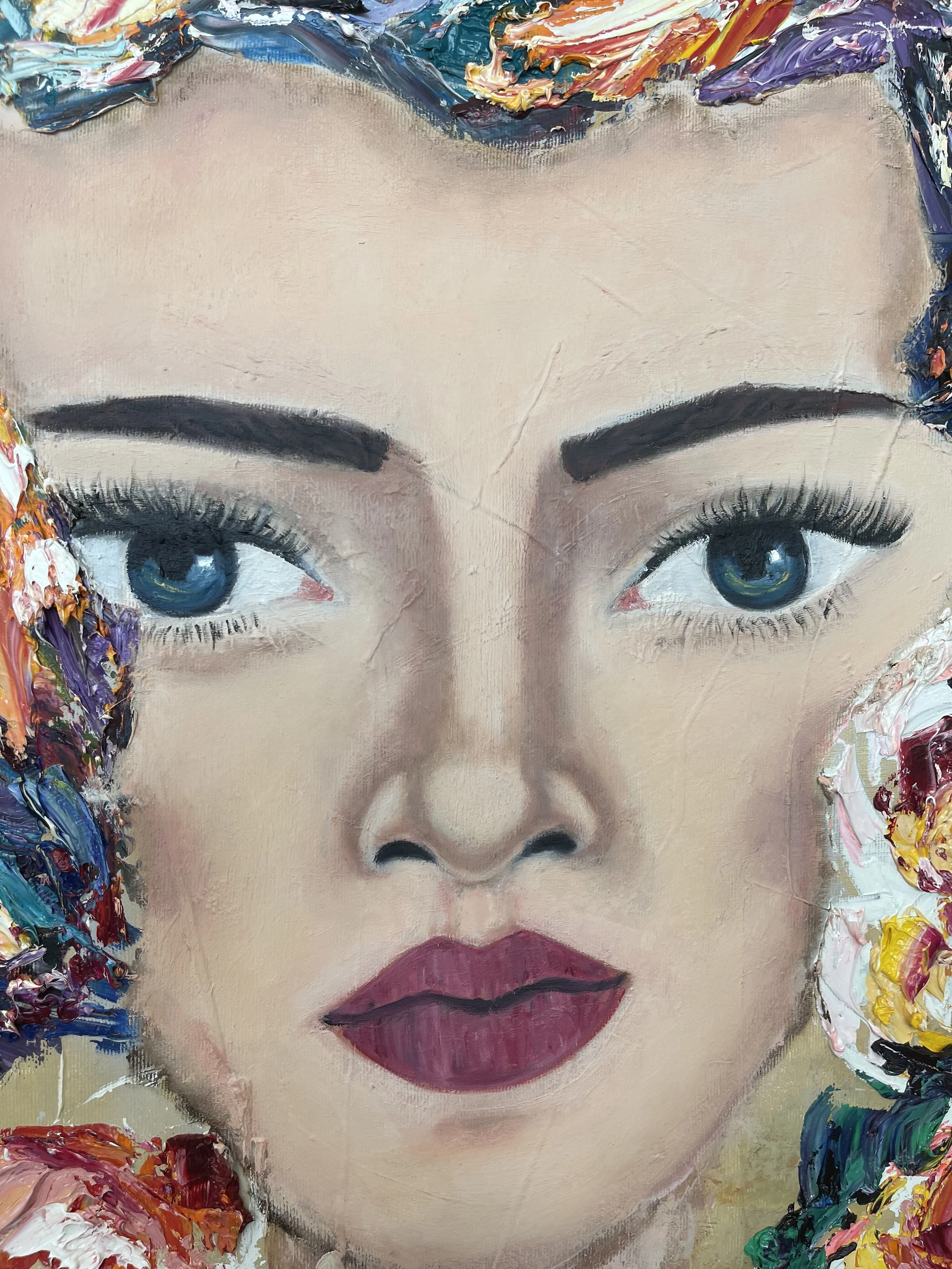 A close-up painting of a woman's face with detailed blue eyes, dark eyebrows, full lips, and colorful textured hair.