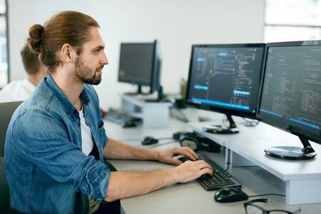 96381583-programming-man-working-on-computer-in-it-office-sitting-at-desk-writing-codes-programmer-typing-dat.jpg
