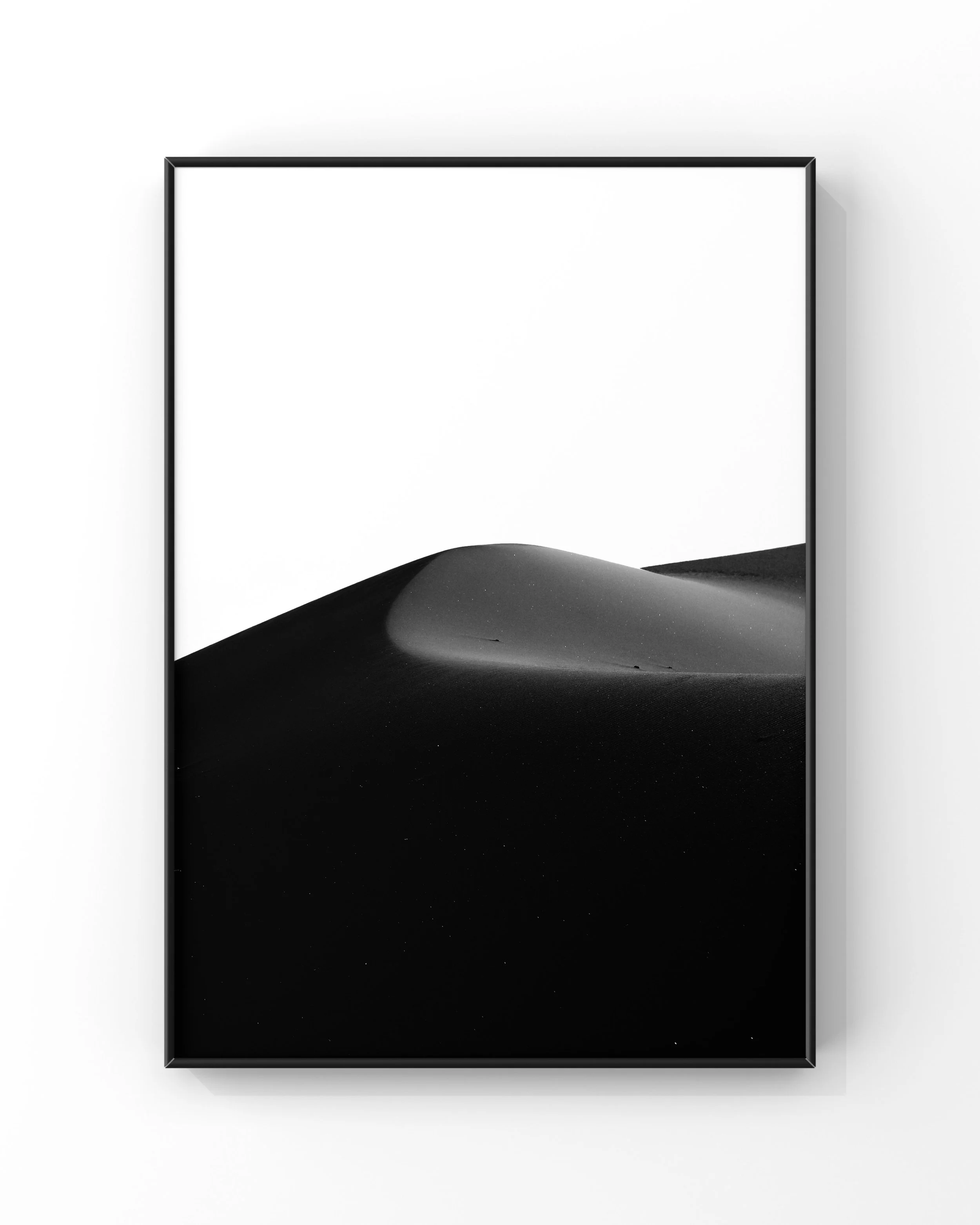 Minimalist black and white photograph of sand dunes in a frame.