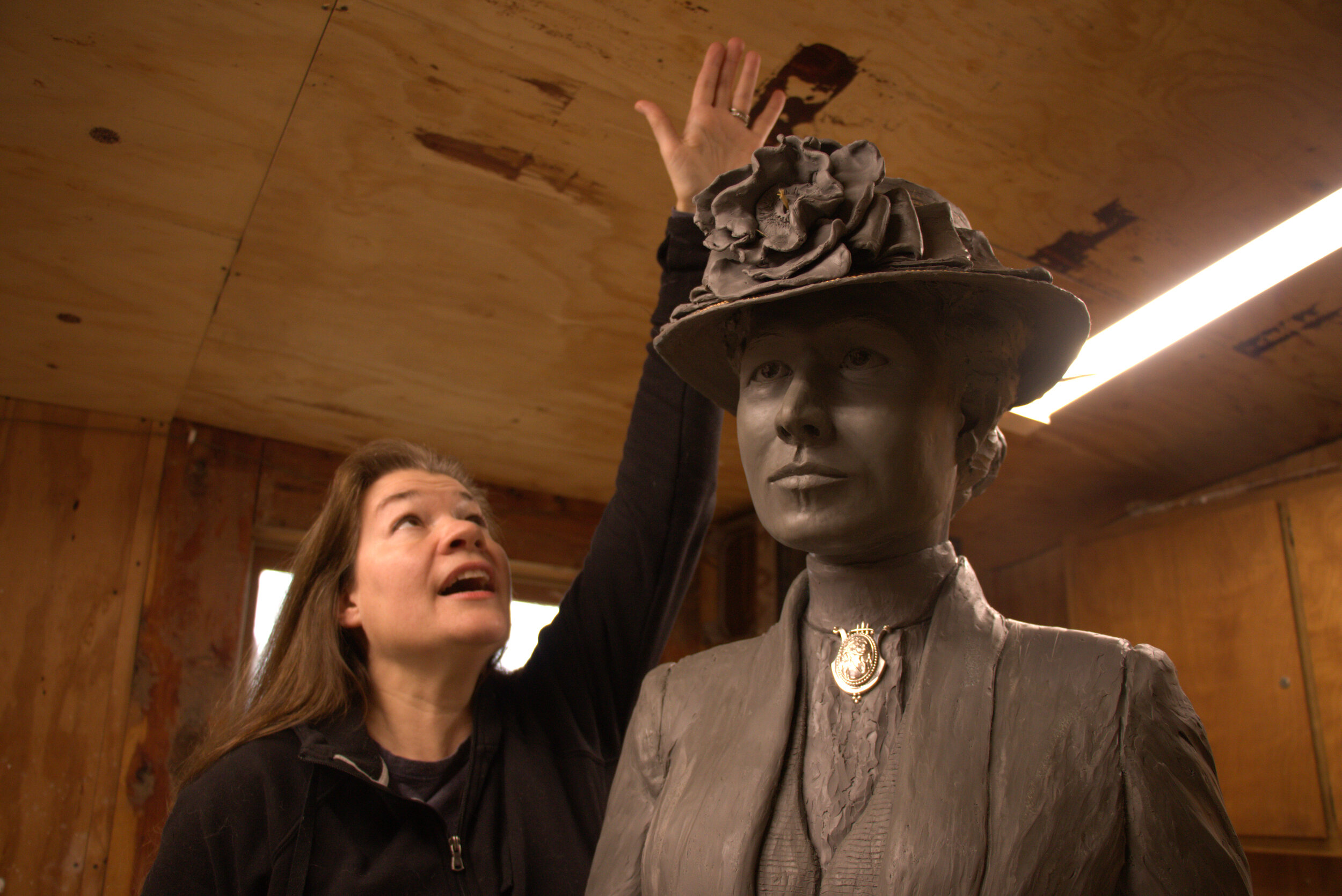 Amanda Matthews demonstrates how tall the finished sculpture of Nettie Depp will be in her studio in Lexington, Kentucky, on February 25, 2020.