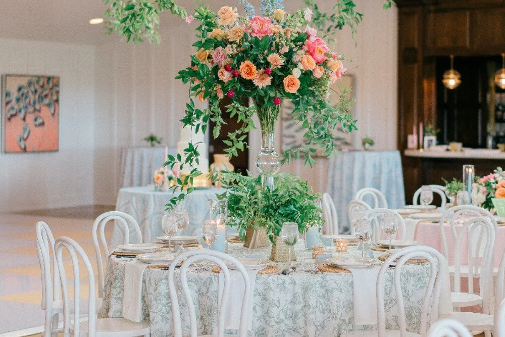 Bright, impressive florals and greenery atop a table in an elegant reception area.