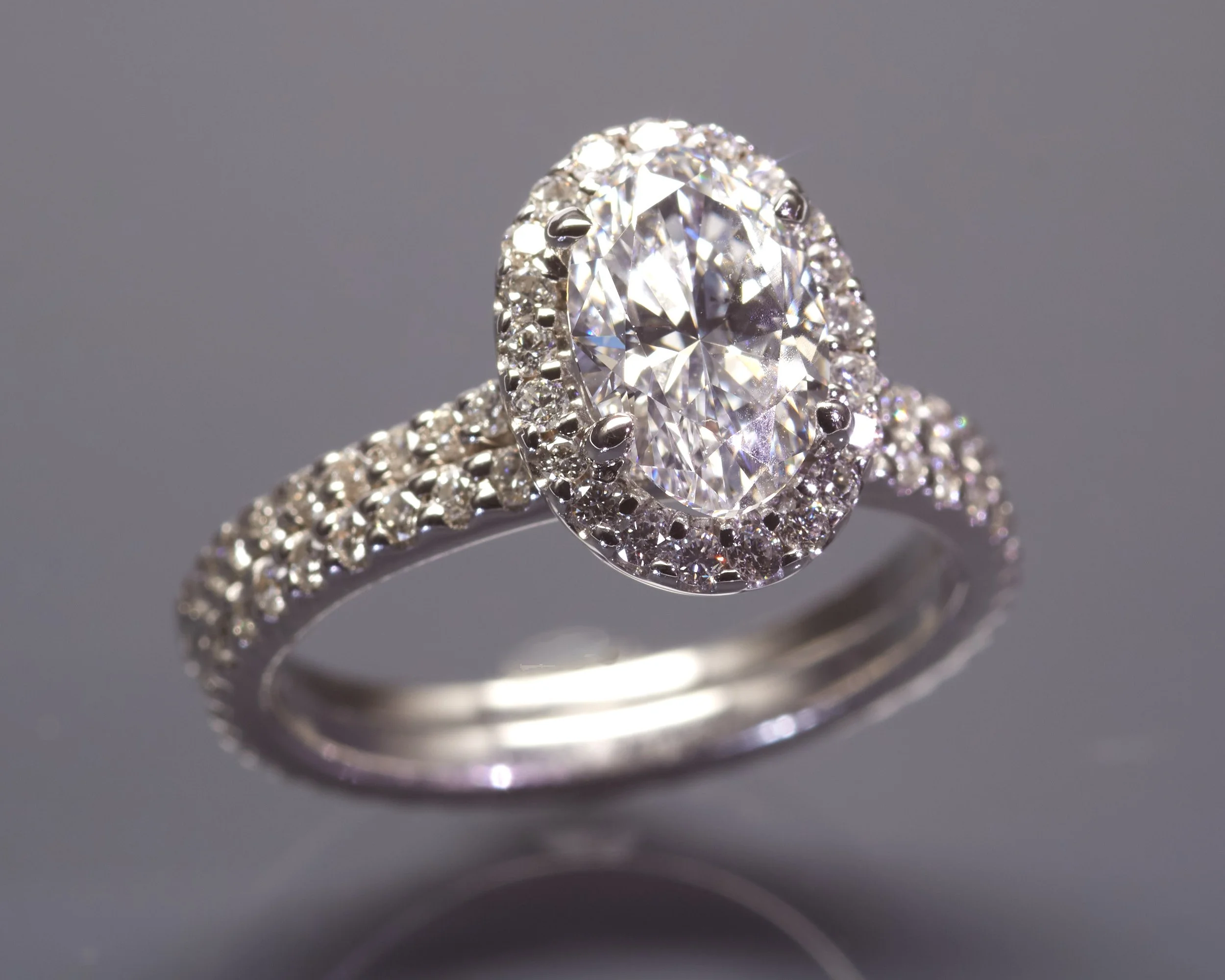 A modern 14k white gold "halo" bridal set. The engagement ring is mounted with 39 round diamonds weighing about 0.39 carat total, surrounding an oval brilliant cut diamond weighing 1.42 carats. It comes with a GIA Diamond Grading Report stating E col