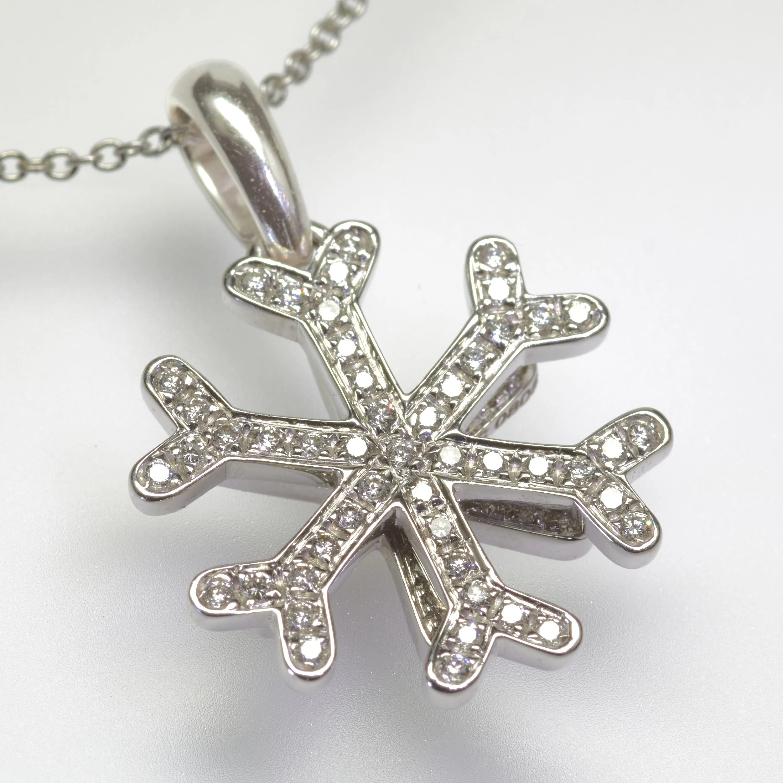 This 18-karat white gold snowflake pendant by designer Marina B twinkles with sixty-seven diamonds weighing about 0.67 carat total. Measures 3/4" across.

