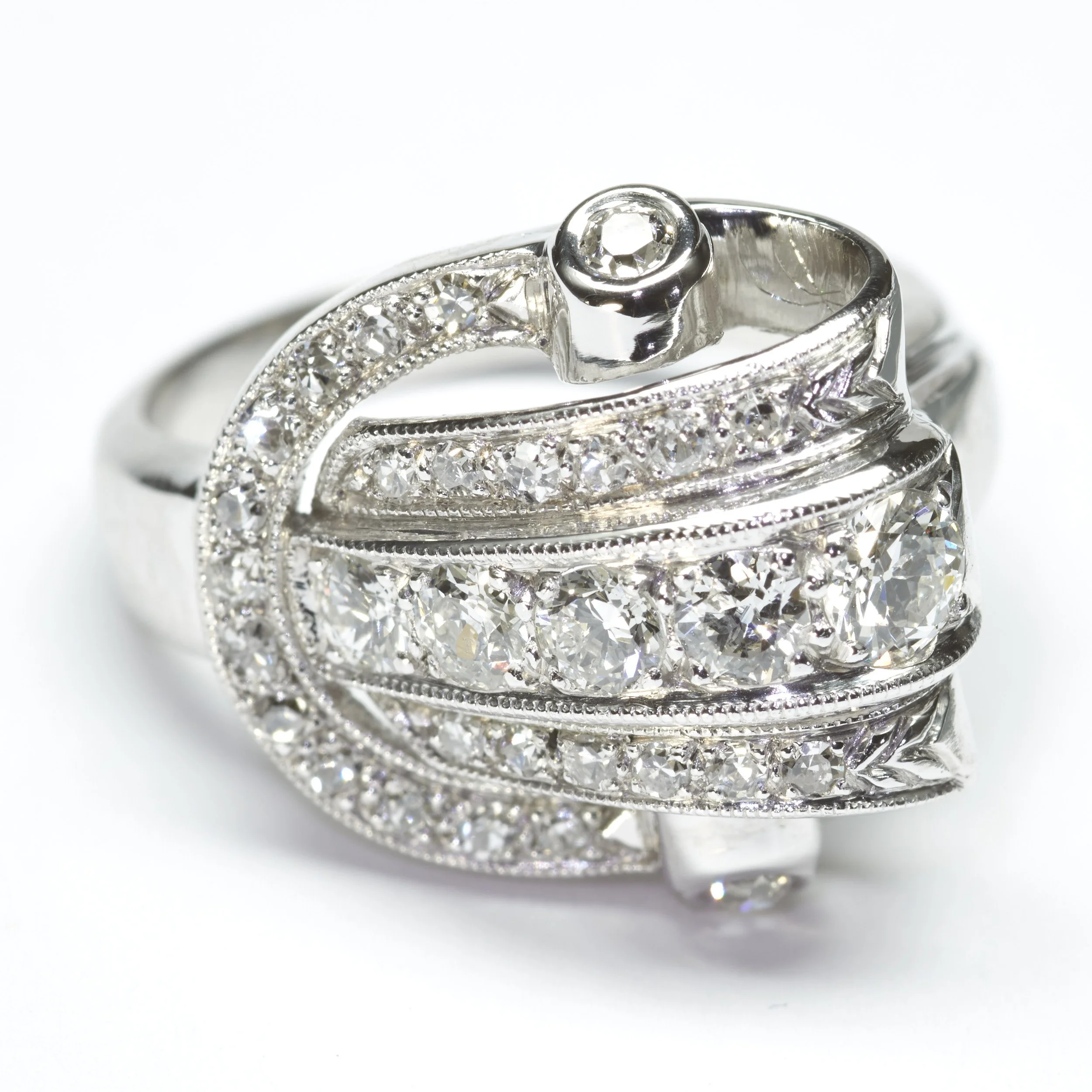 A gorgeous Retro ring from the 1940s in a buckle design in palladium, set with 31 diamonds weighing about 1.00 carat total.