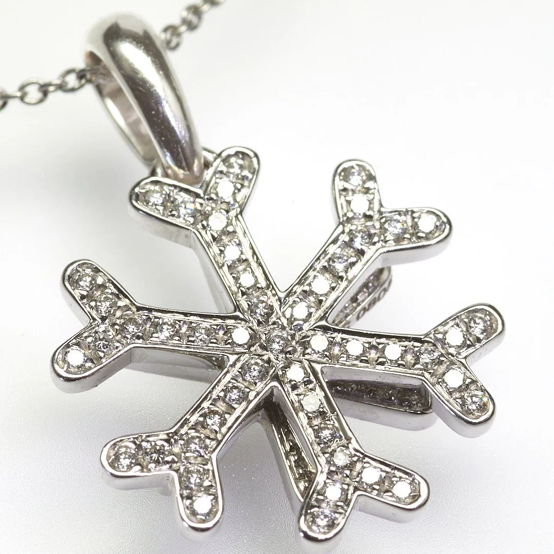 Sparkling 18-karat white gold snowflake pendant by famed designer (and Bulgari family member) Marina B, se with sixty-seven diamonds weighing about 0.67 carat total. Measures 3/4" across.