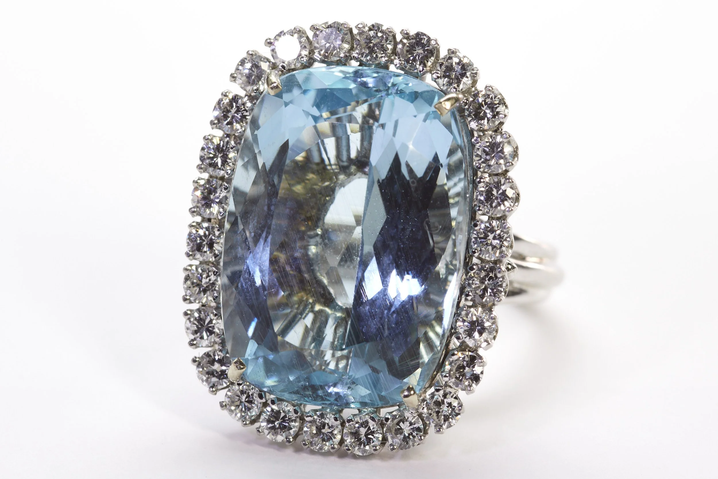 A beautifully hand-crafted wire ring in 14-karat white gold, displaying an antique cushion shaped aquamarine weighing about 22 carats; and surrounded by 26 diamonds weighing about 2.00 carats total. 
