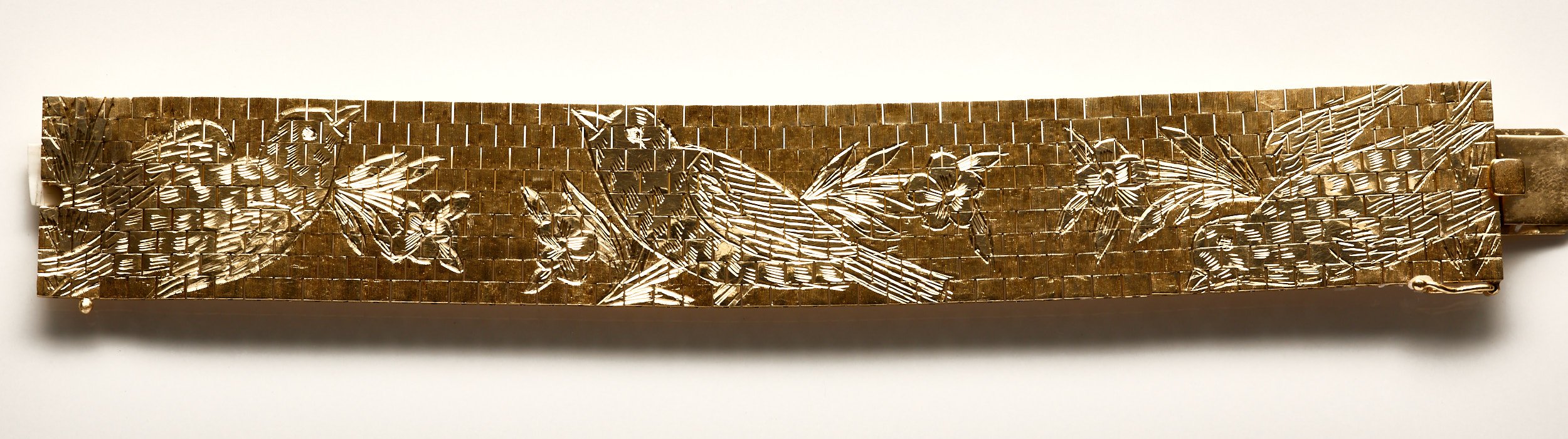 This remarkable 14-karat yellow gold mesh bracelet displays three high polished, hand-engraved birds with foliage on a satin-finished background. Measures just over 1" wide x 7 3/8" long.