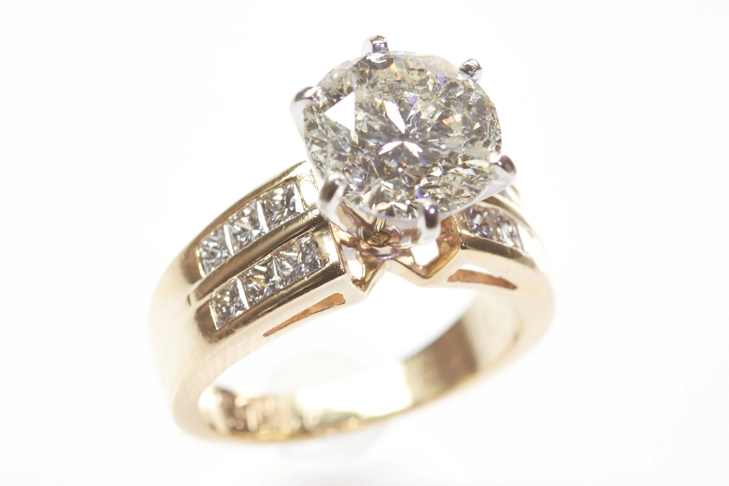 4-karat yellow gold engagement ring set with a round brilliant cut diamond weighing 4.06 carats and smaller princess-cut diamonds below.