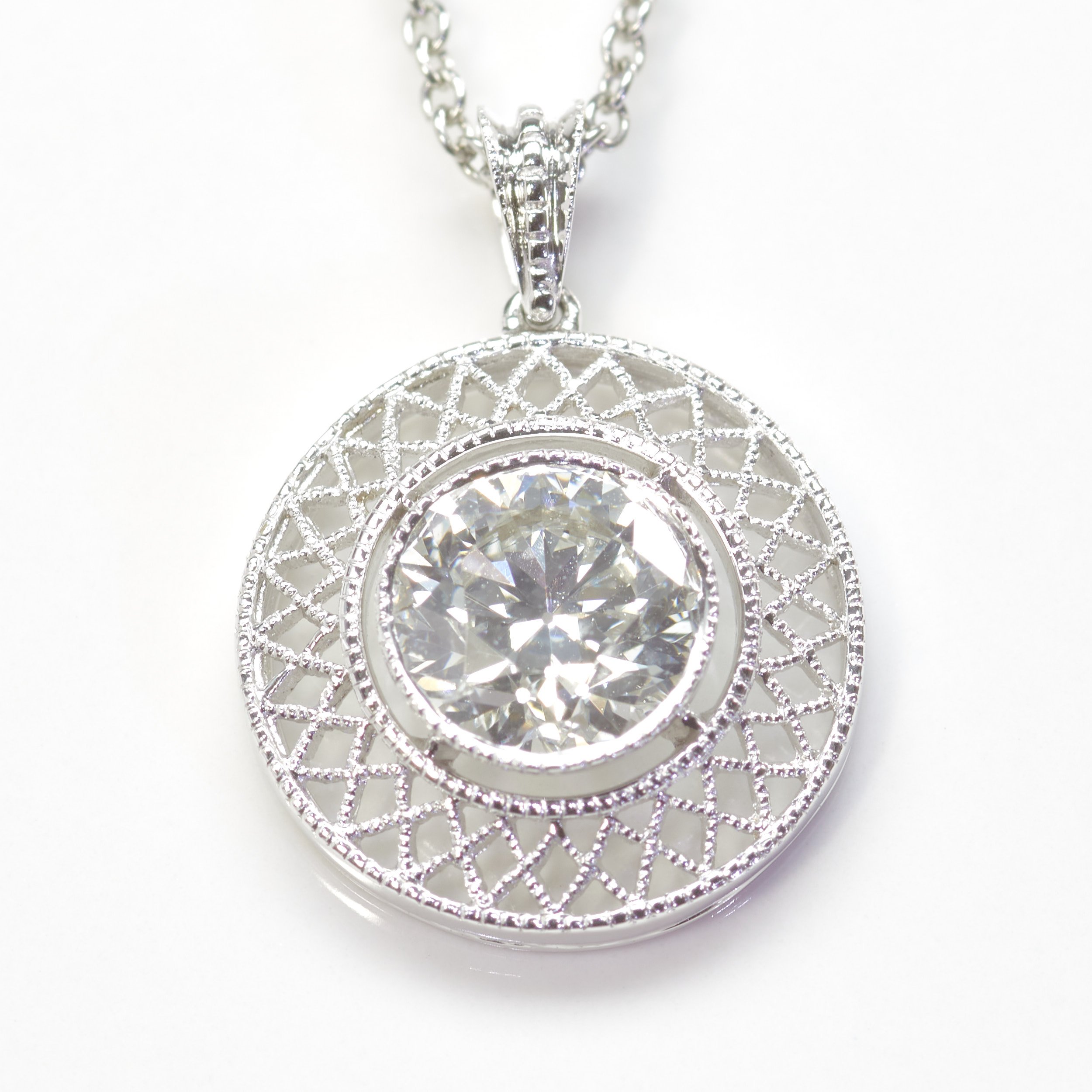 A platinum tube-set "merry widow" pendant with filigree surround is set with a round diamond weighing 0.99 carat, having G color and SI2 clarity. Withy 18" neck chain.
