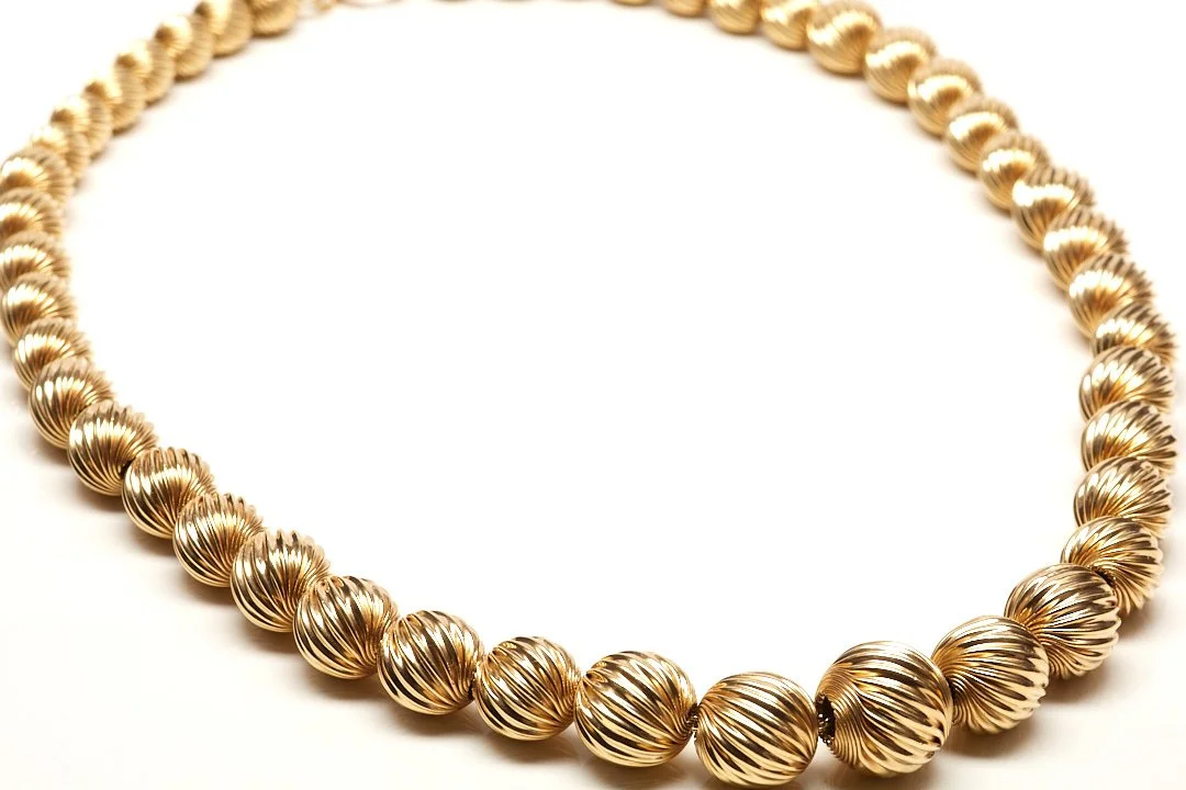 Mid Twentieth Century necklace, 15 1/2" long, in 14-karat yellow gold with twist-design, corrugated beads graduating from 6.5 to 12.5 mm. 