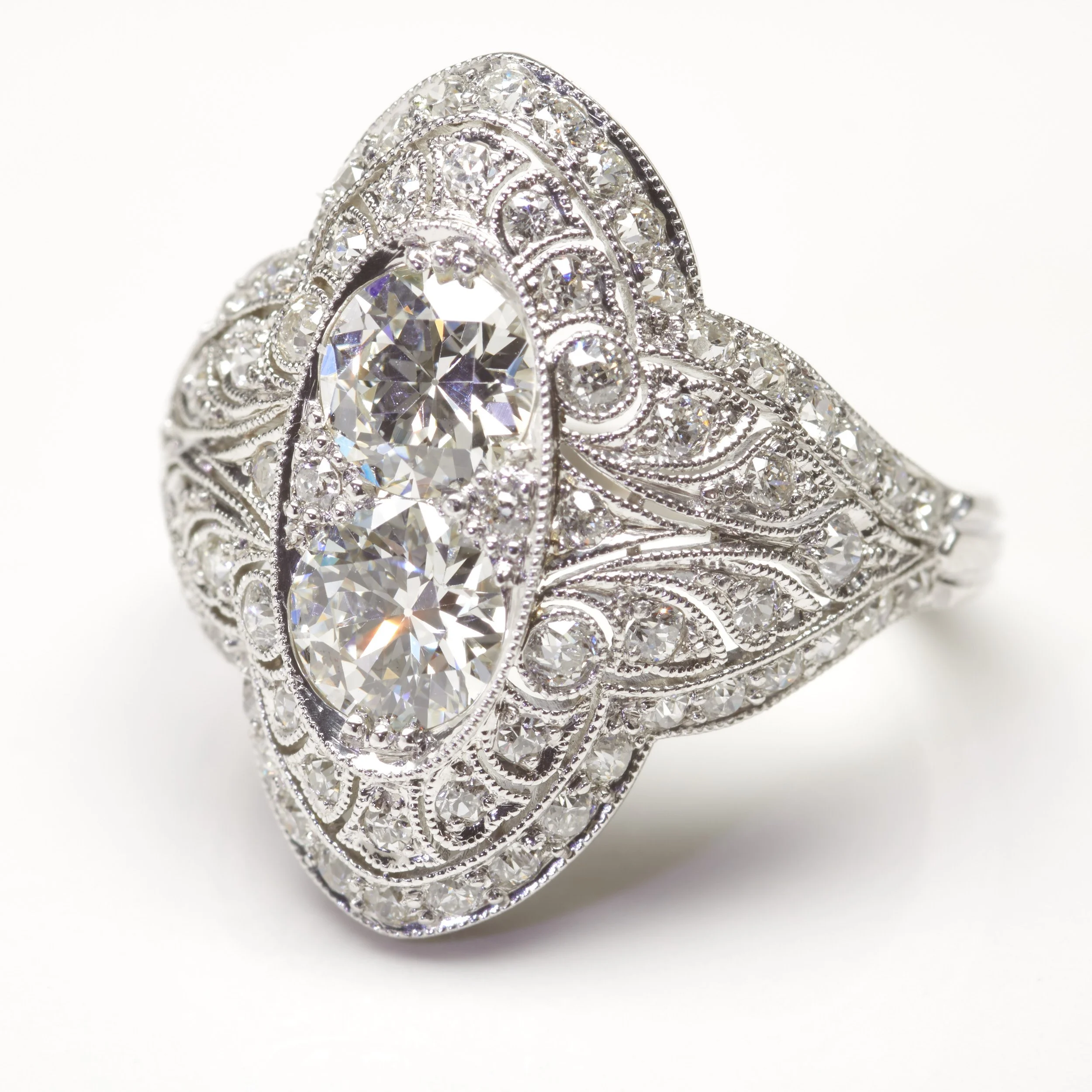 A spectacular "moi et toi" platinum ring from the Edwardian era (c. 1910). It centers two old 
European cut diamonds together weighing about 1.20 carats, and 68 smaller ones weighing about 1.15 carats total. With delicate milgrain throughout. The fac