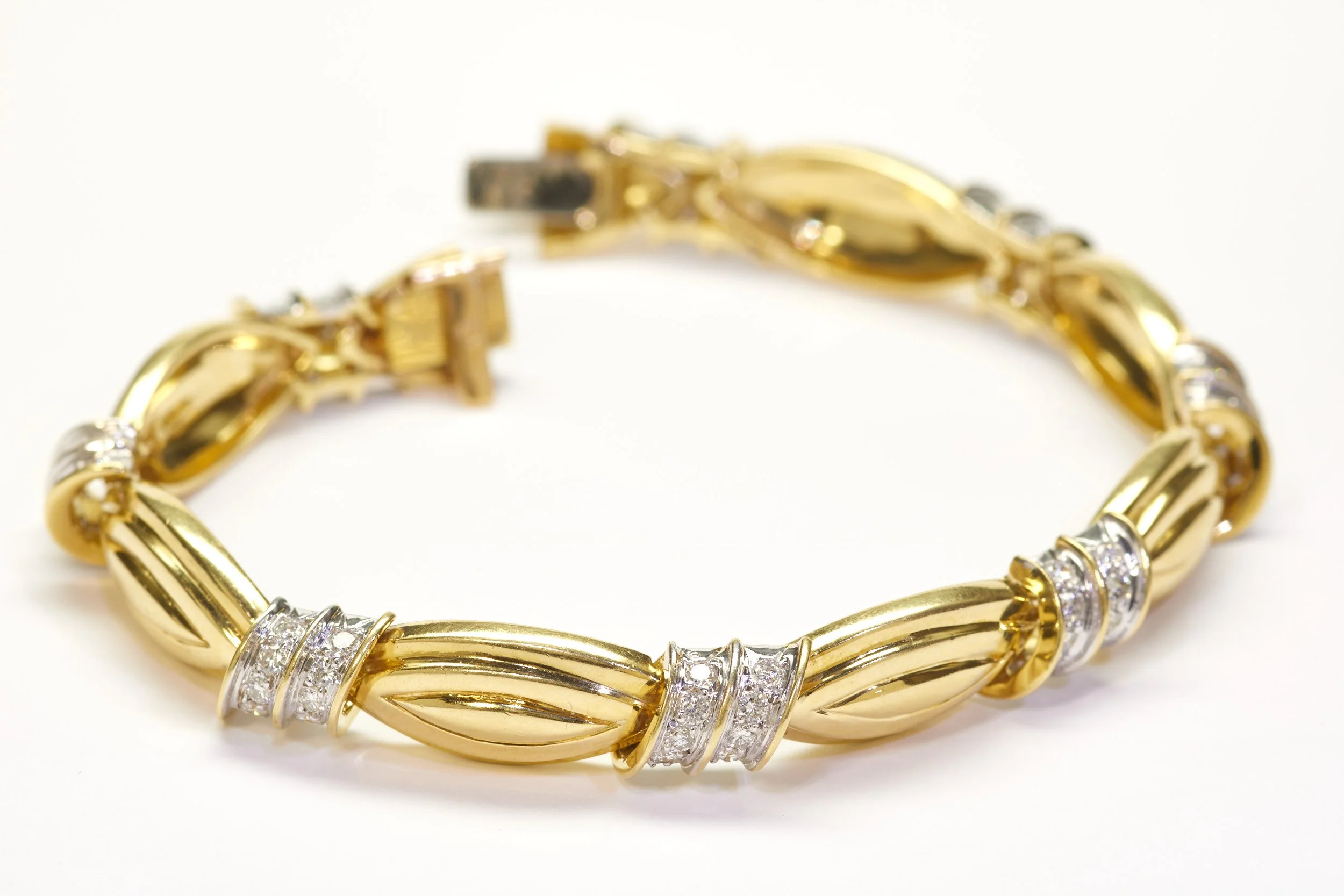 A stylish 18-karat yellow gold bracelet alternating diagonal two-row diamond links with fluted oblong links, signed by Chalson. Measures 3/8" wide and 7 3/8" long.