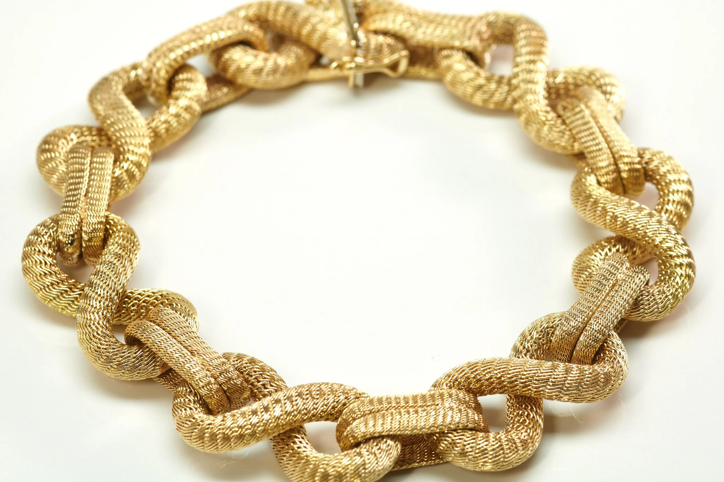 An imposing Italian bracelet in 18-karat yellow gold measures 5/8" wide and 8 3/4" long, with alternating figure-eight and bar links of tubular mesh.