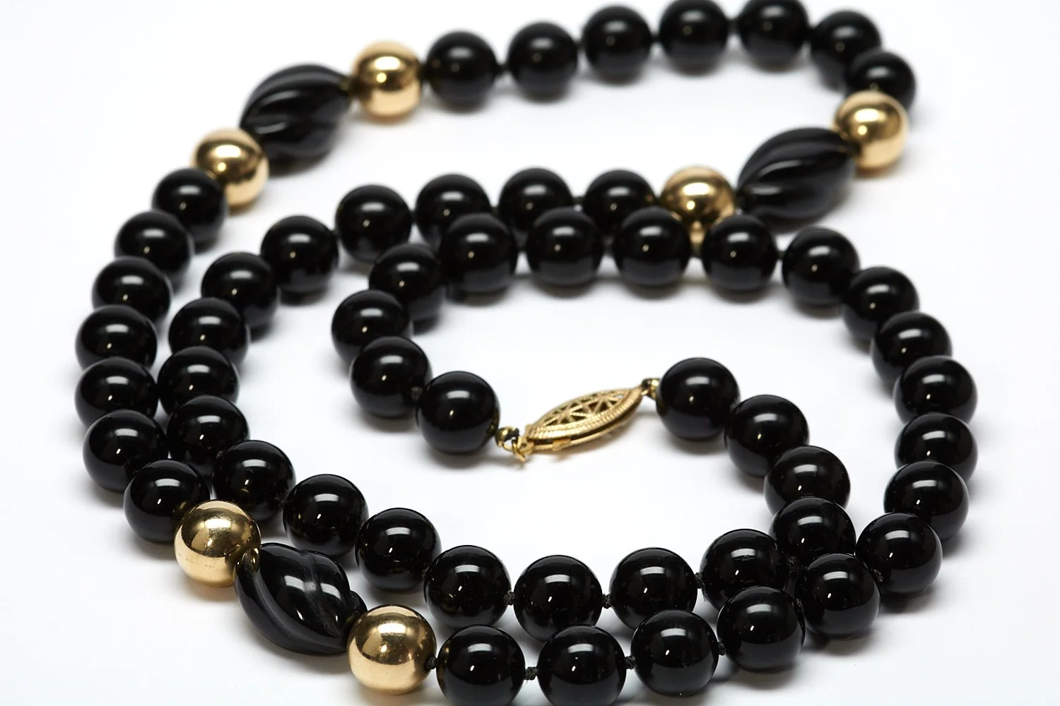 Fifty-four black onyx beads each measuring 10 mm, six in 14-karat yellow gold, and three more gadrooned in black onyx set off this necklace measuring 28" long.