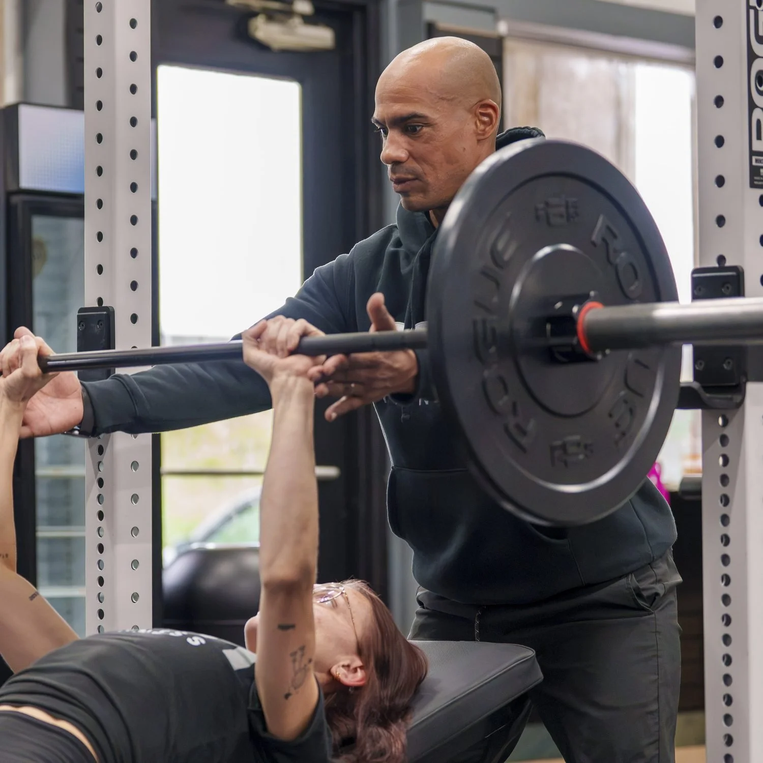 A CSH Fitness coach spotting a client's bench press during a one-on-one session