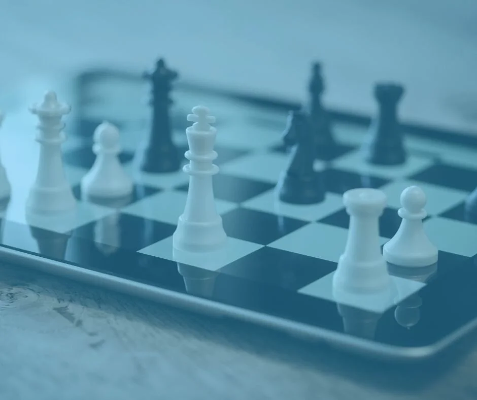 Close-up of a chessboard with white and black chess pieces set up, viewed from a low angle.