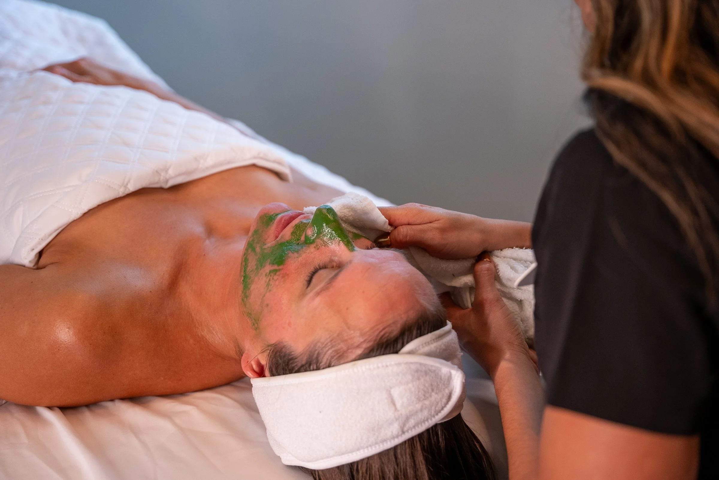 Woman receiving a green facial with her eyes closed.