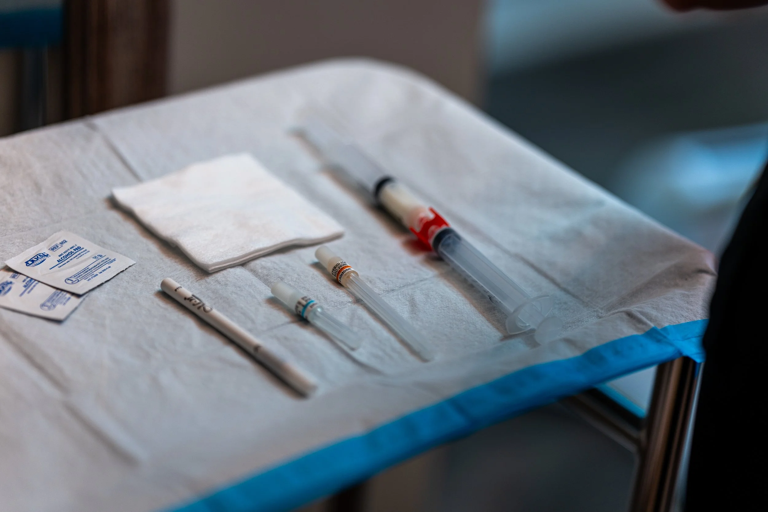 Injectable treatment supplies including syringes, needles, gauze, and alcohol pads arranged on sterile tray.