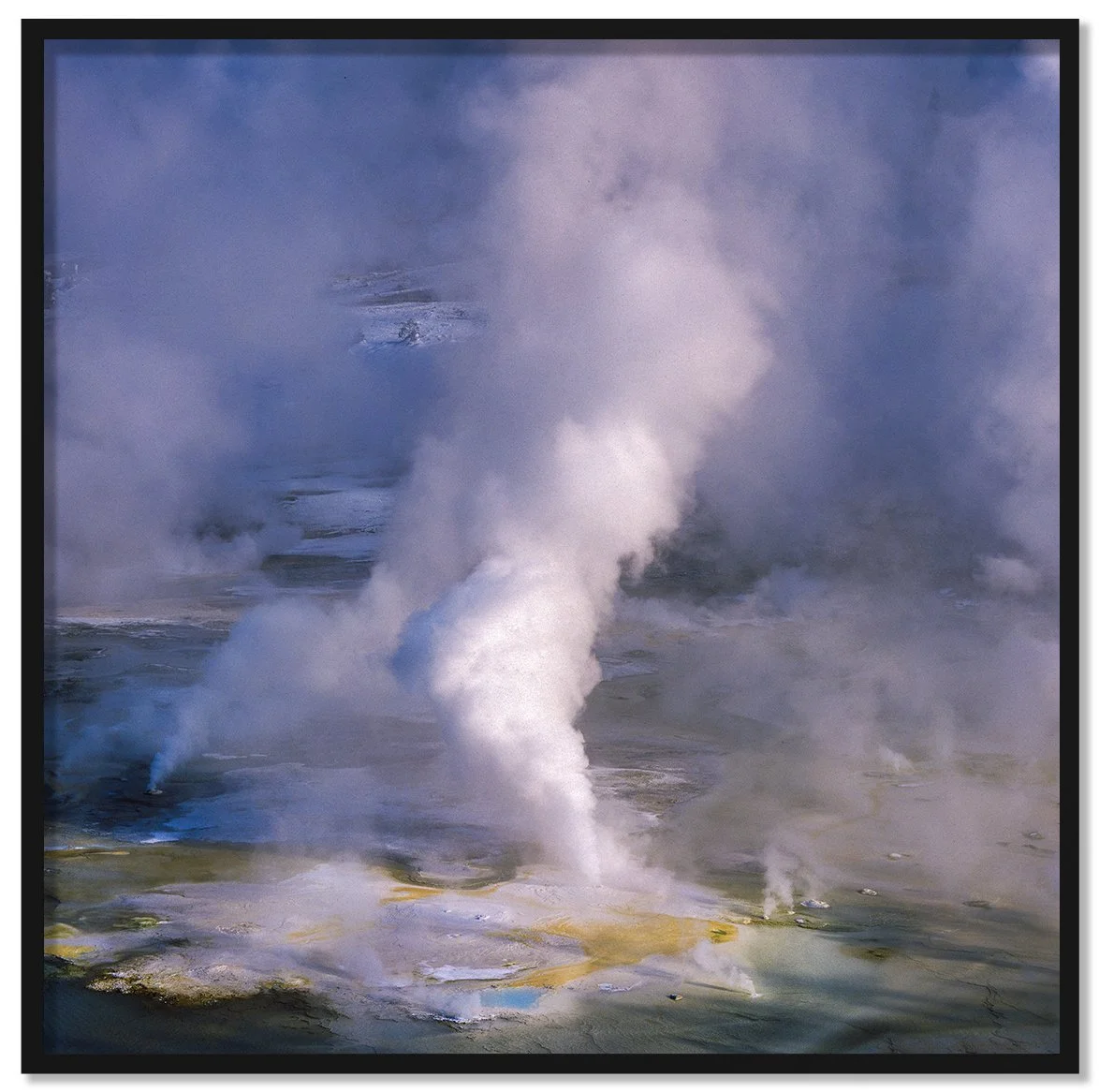 Geyser II framed fine art print by Luca Marziale, white steam column rising from erupting geyser over yellow and blue thermal pools in winter, Yellowstone National Park