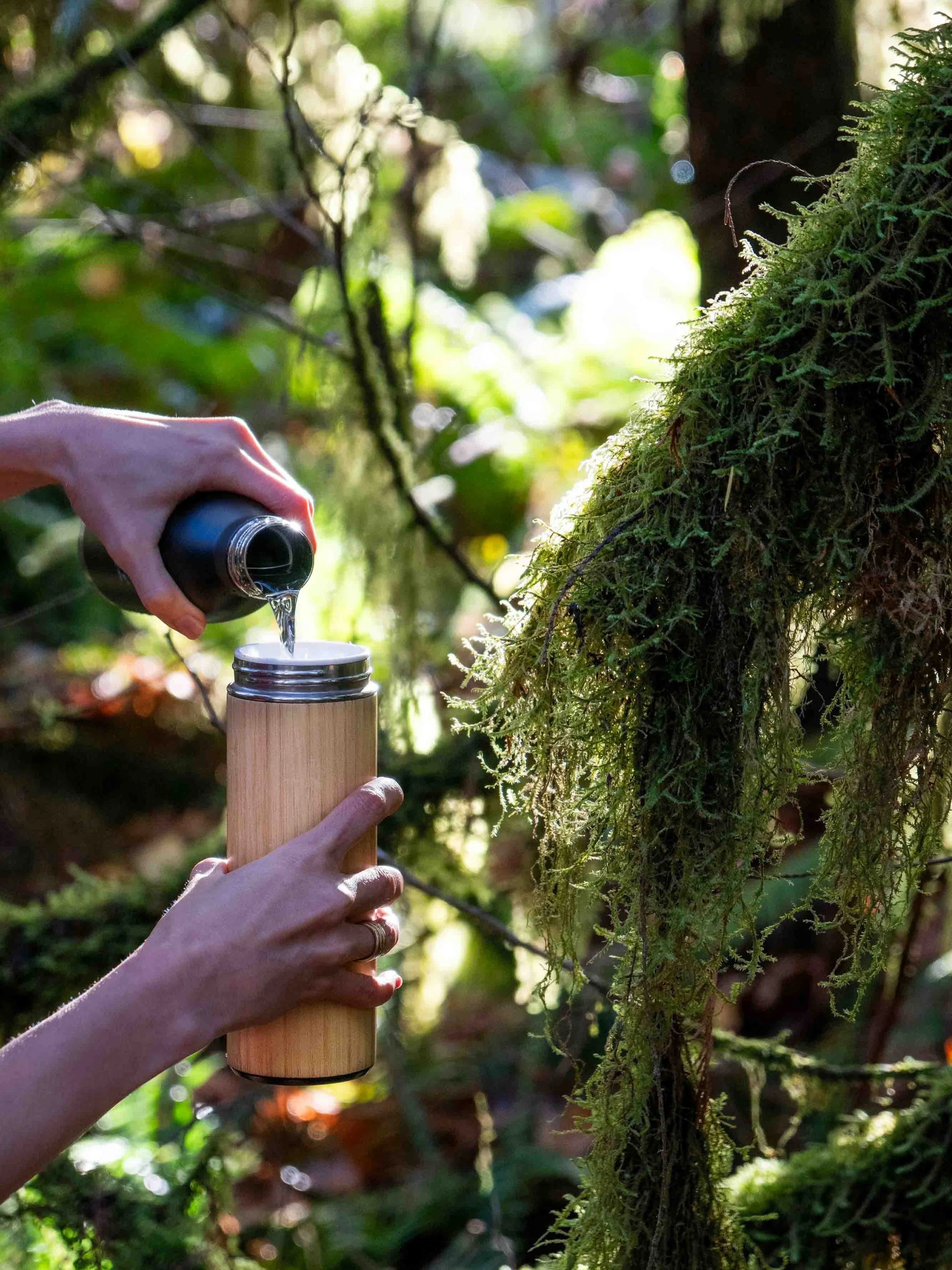 Pouring water in a ceramic flask for tea in the forest