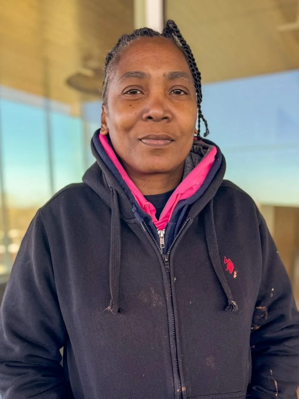Headshot of a woman in a black hooded sweatshirt, smiling