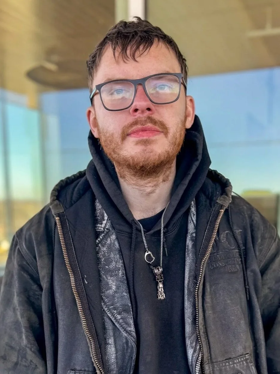 Headshot of man in glasses smiling at camera, in black sweatshirt