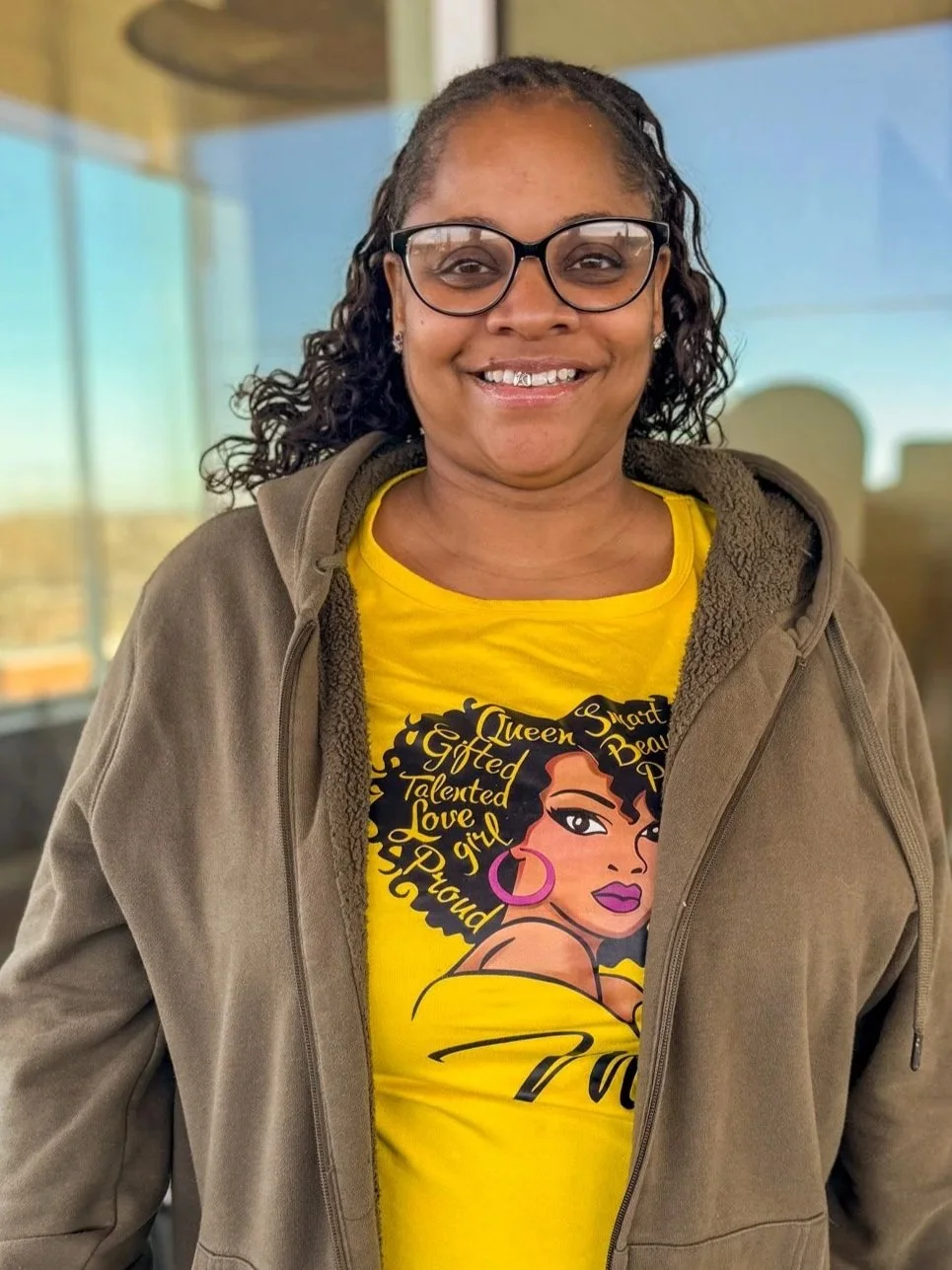 headshot of smiling woman in yellow shirt and green jacket