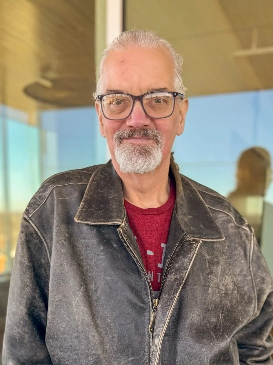 Headshot of man with white hair and beard smiling at the camera