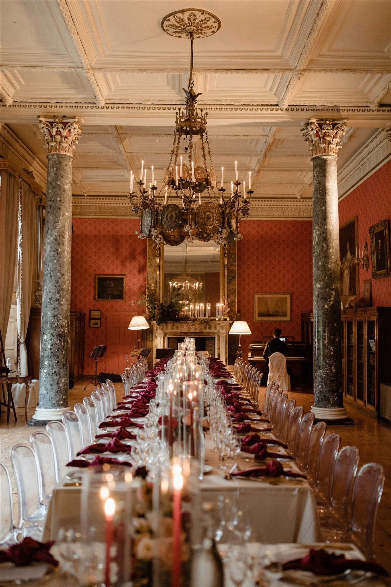 Moody long-table wedding dinner at Bantry House with rich red florals, candles, and dramatic period interiors.