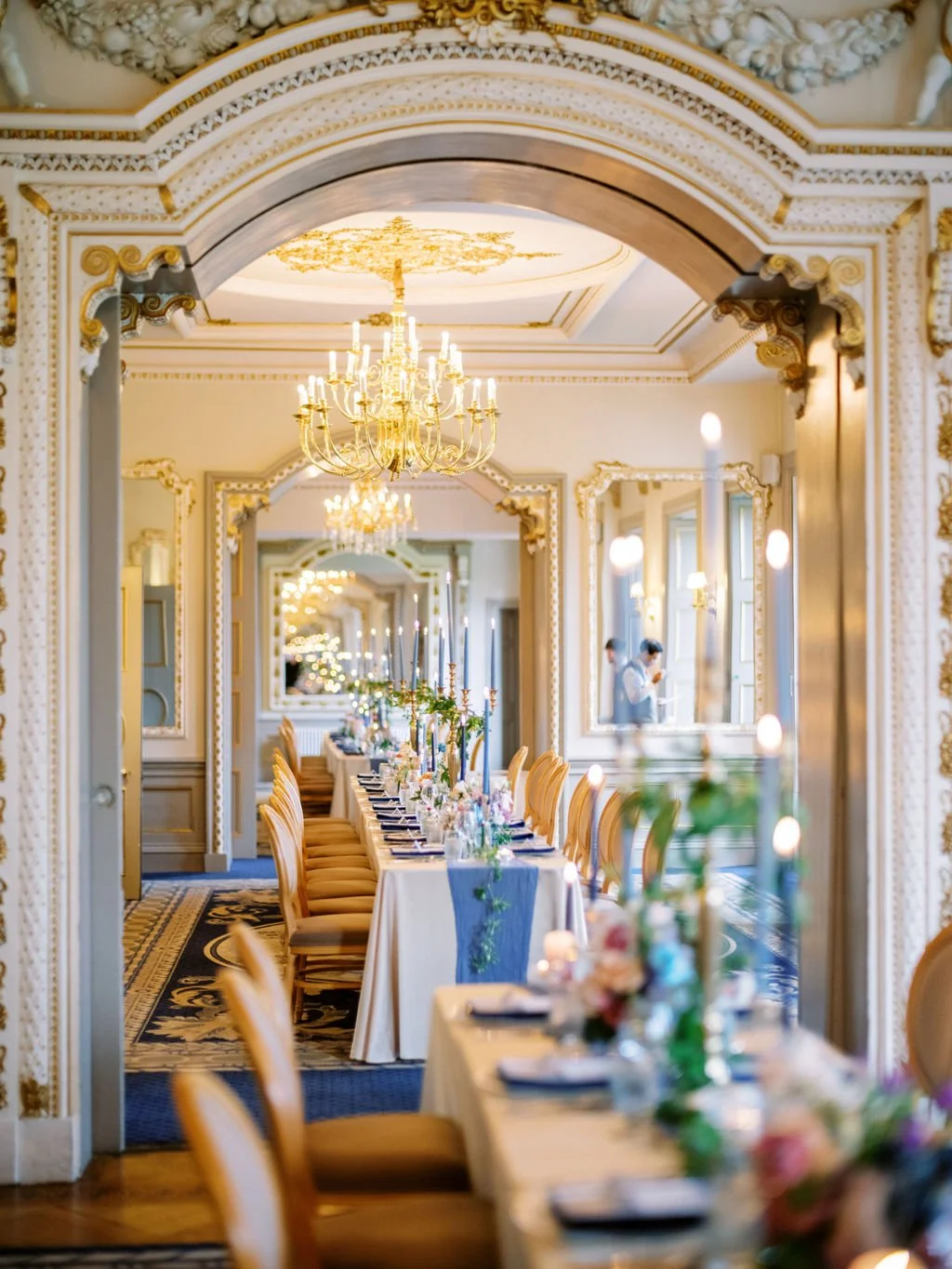 Markree Castle ballroom wedding reception long table with gold chandelier blue tapers and gilt mirrors Ireland