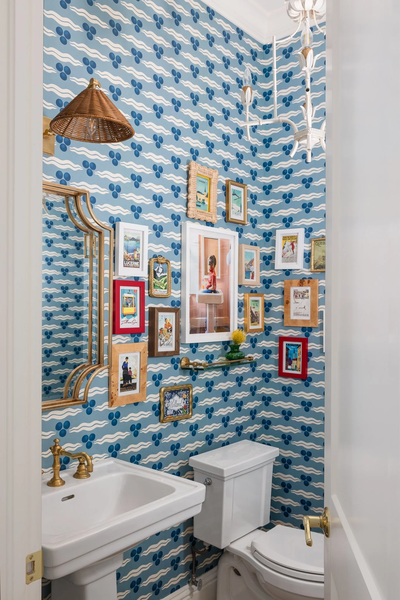 Even a powder room can be used to showcase a gallery wall of small art pieces. The bold blue wallpaper and rattan vanity light create even more texture and visual interest.