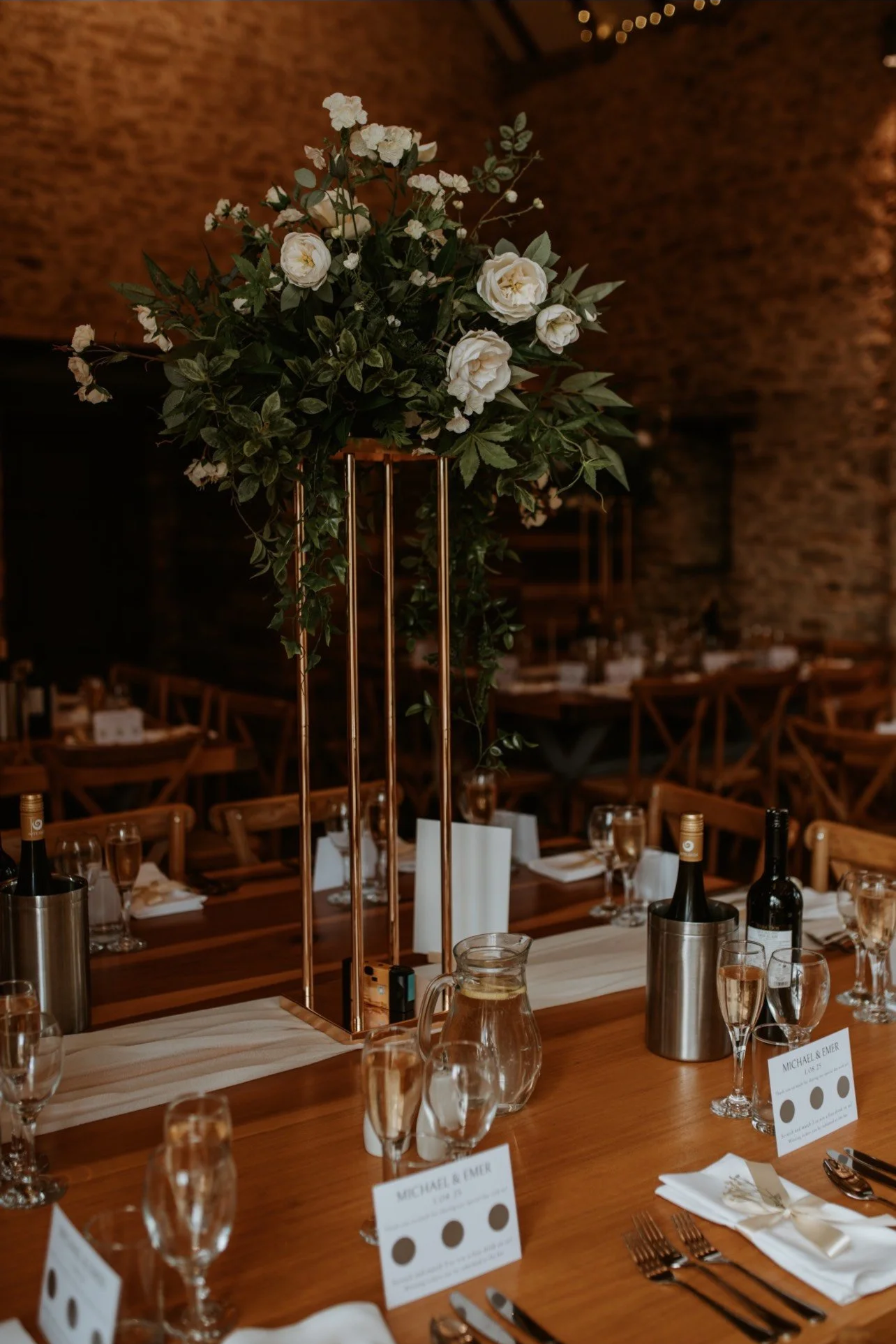 Tall artificial flower centrepiece with white flowers and greenery at The Great Barn Aynho