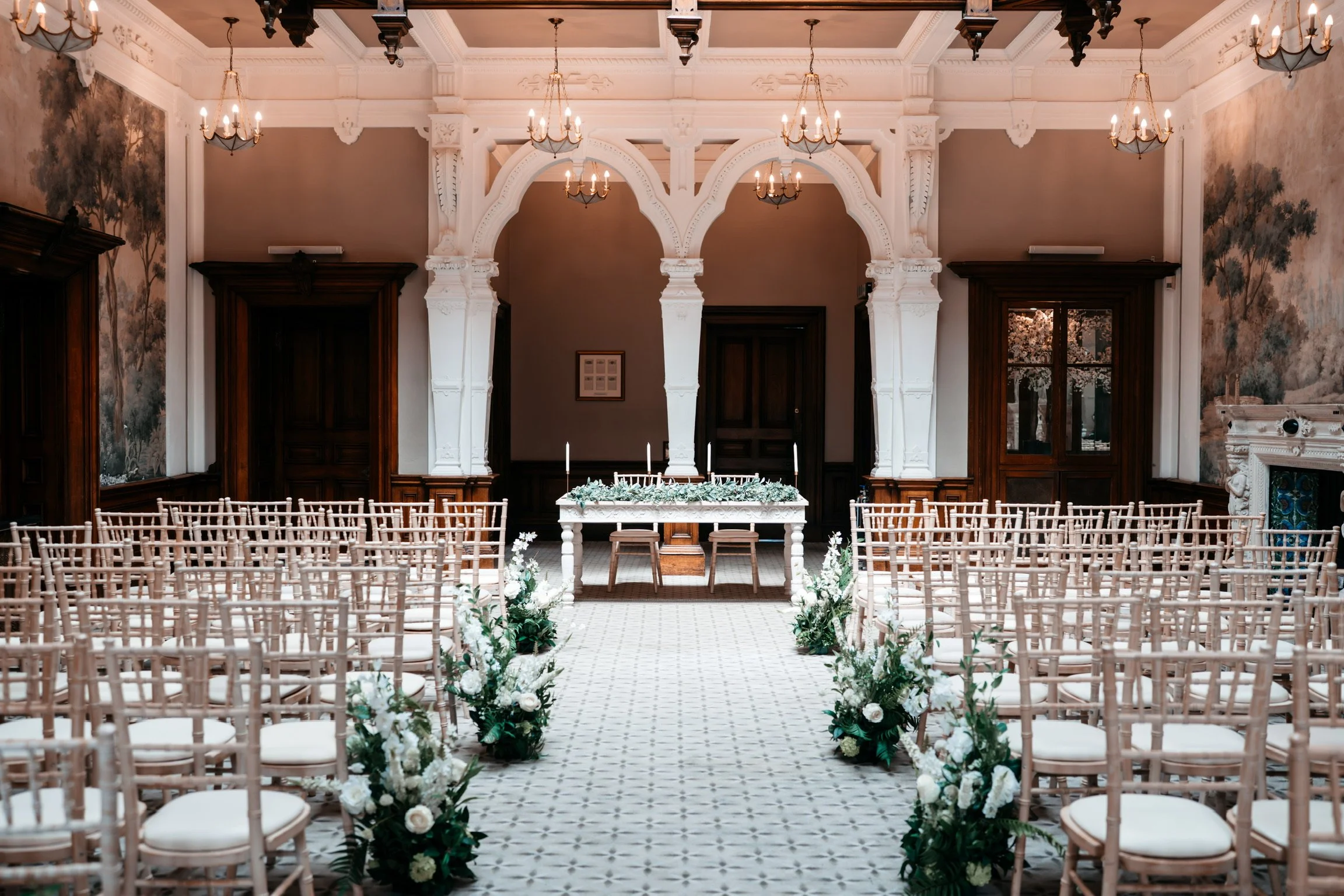 Wedding ceremony aisle decorated with white artificial flowers and greenery