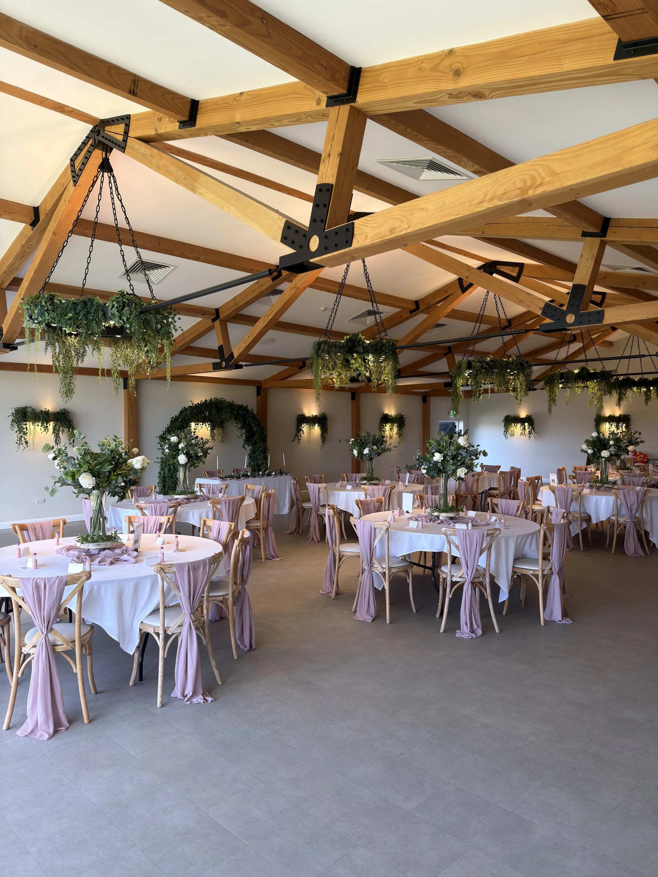 Wedding reception at Hanbury Barns styled with artificial floral centrepieces and hanging greenery