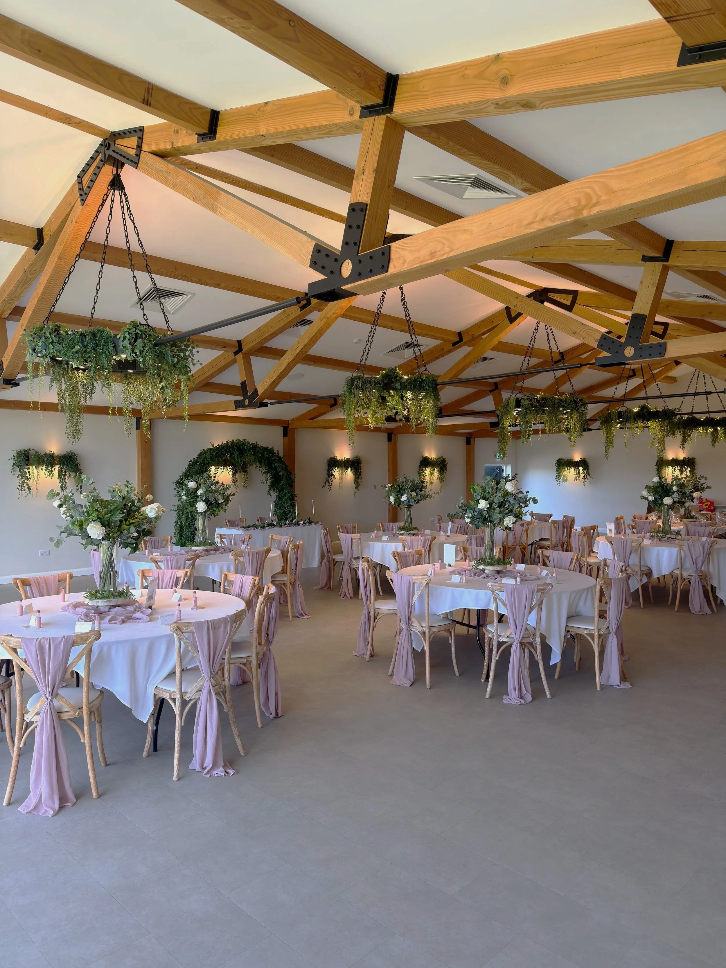 Hanbury Barns in Staffordshire styled with hanging greenery and artificial floral centrepieces