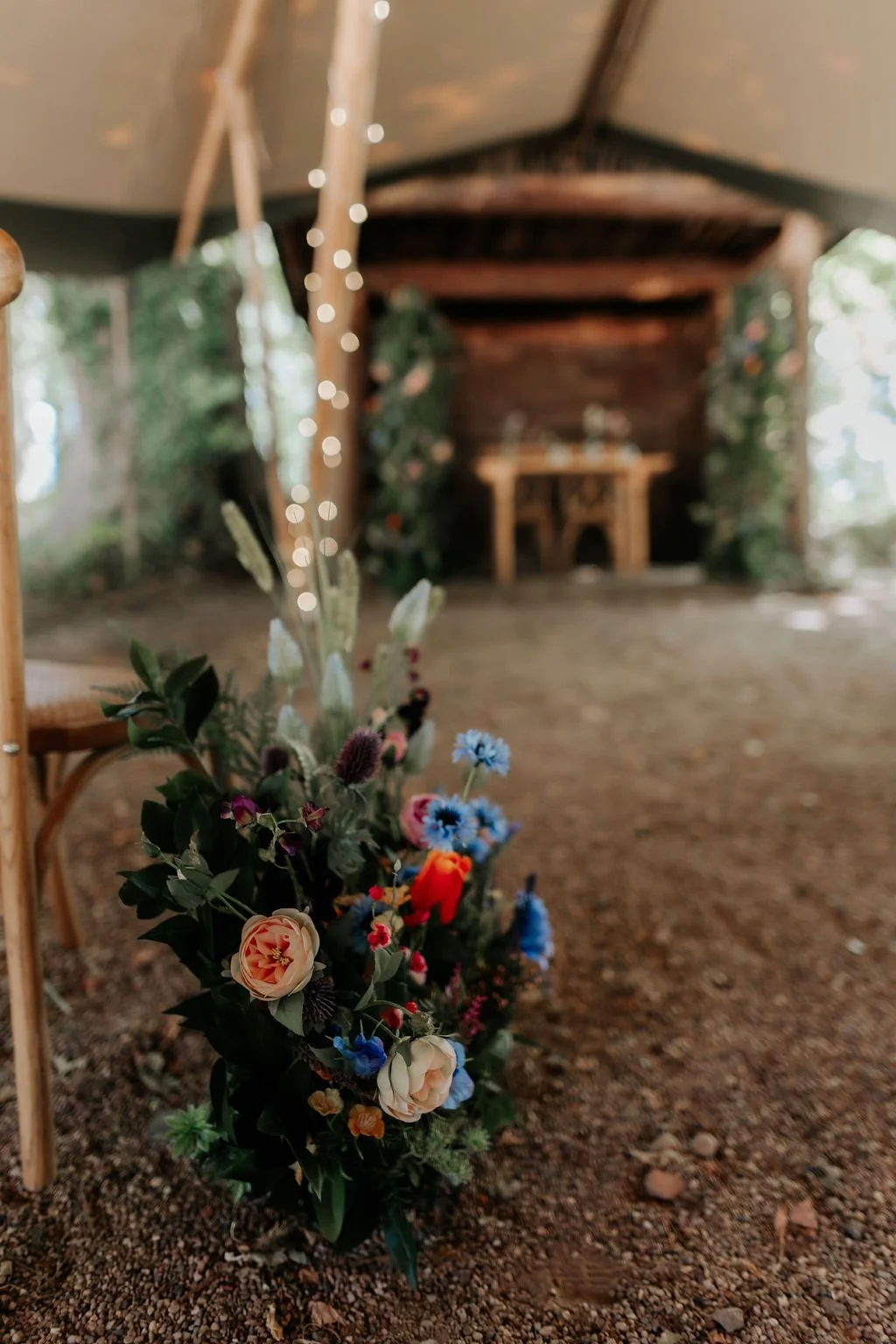 Colourful artificial wedding flowers lining the ceremony aisle, with the wooden ceremony shelter in the background at Whatton House.