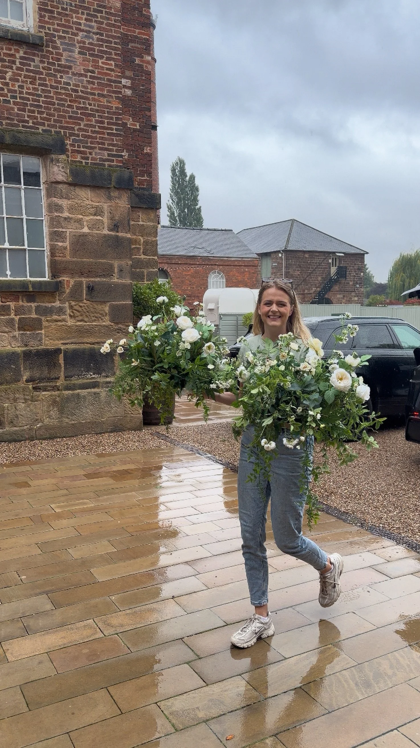 White artificial wedding flower arrangements being carried into a wedding venue The West Mill Derbyshire