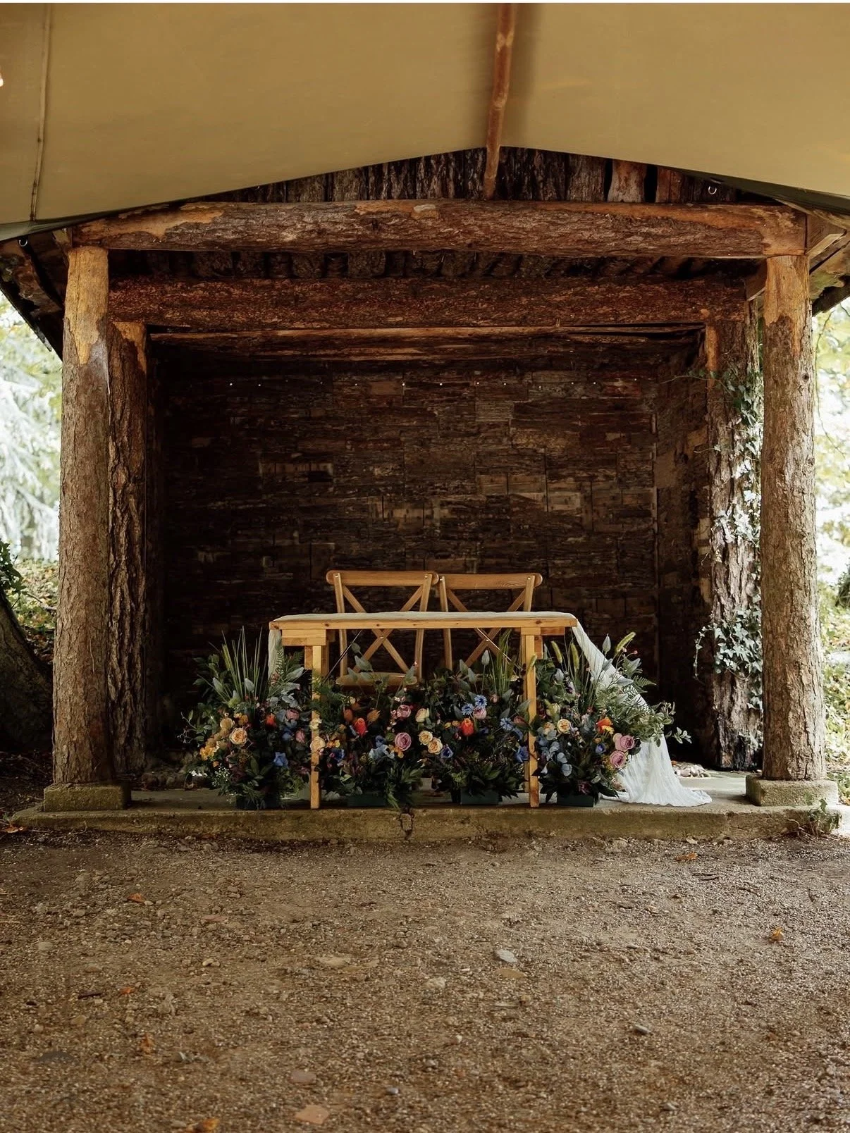 Colourful artificial wedding flowers styled along a sweetheart table at Tipis Whatton House