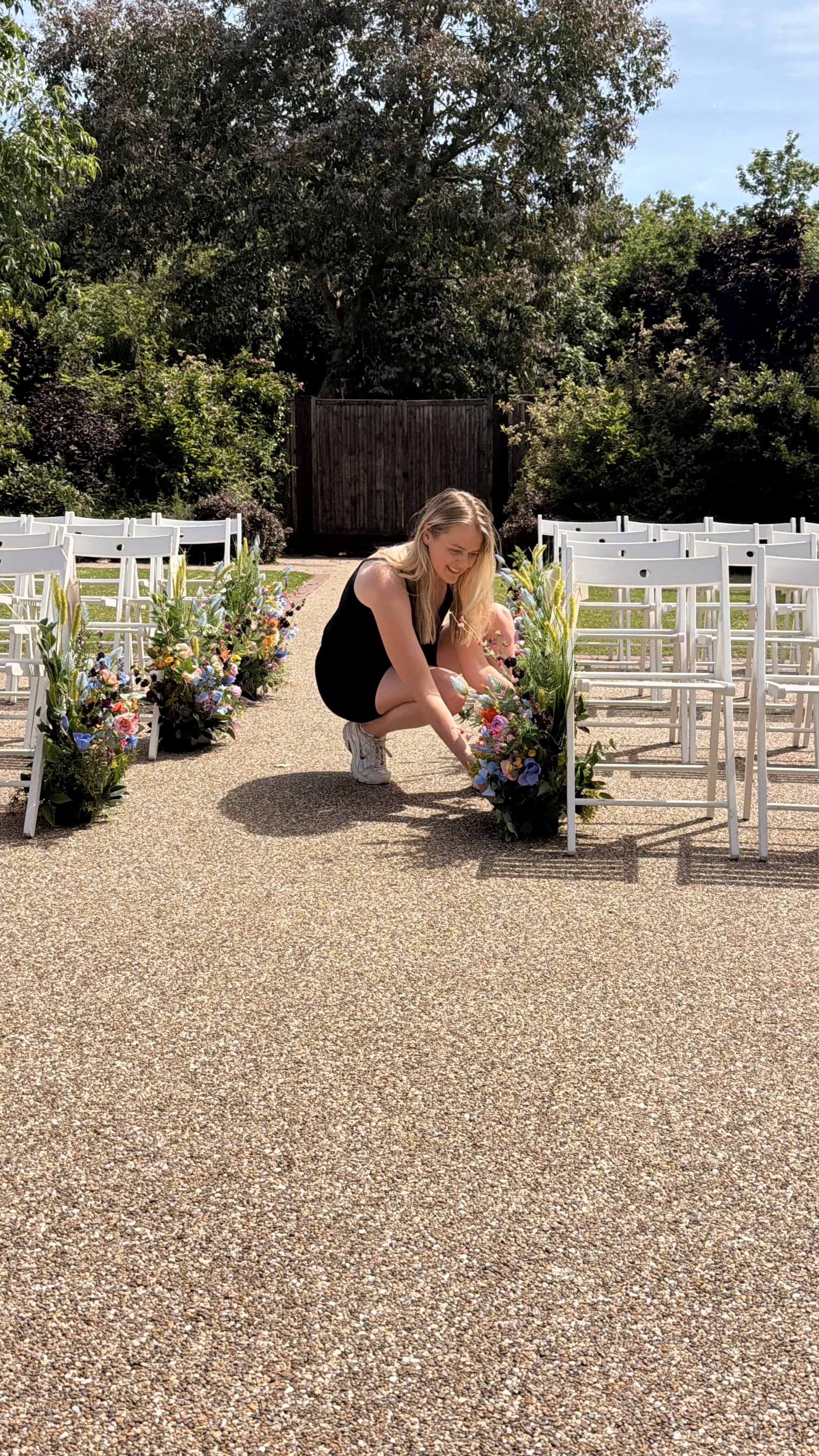 Setting up colourful artificial flower aisle arrangements for a wedding ceremony Hanbury Barns