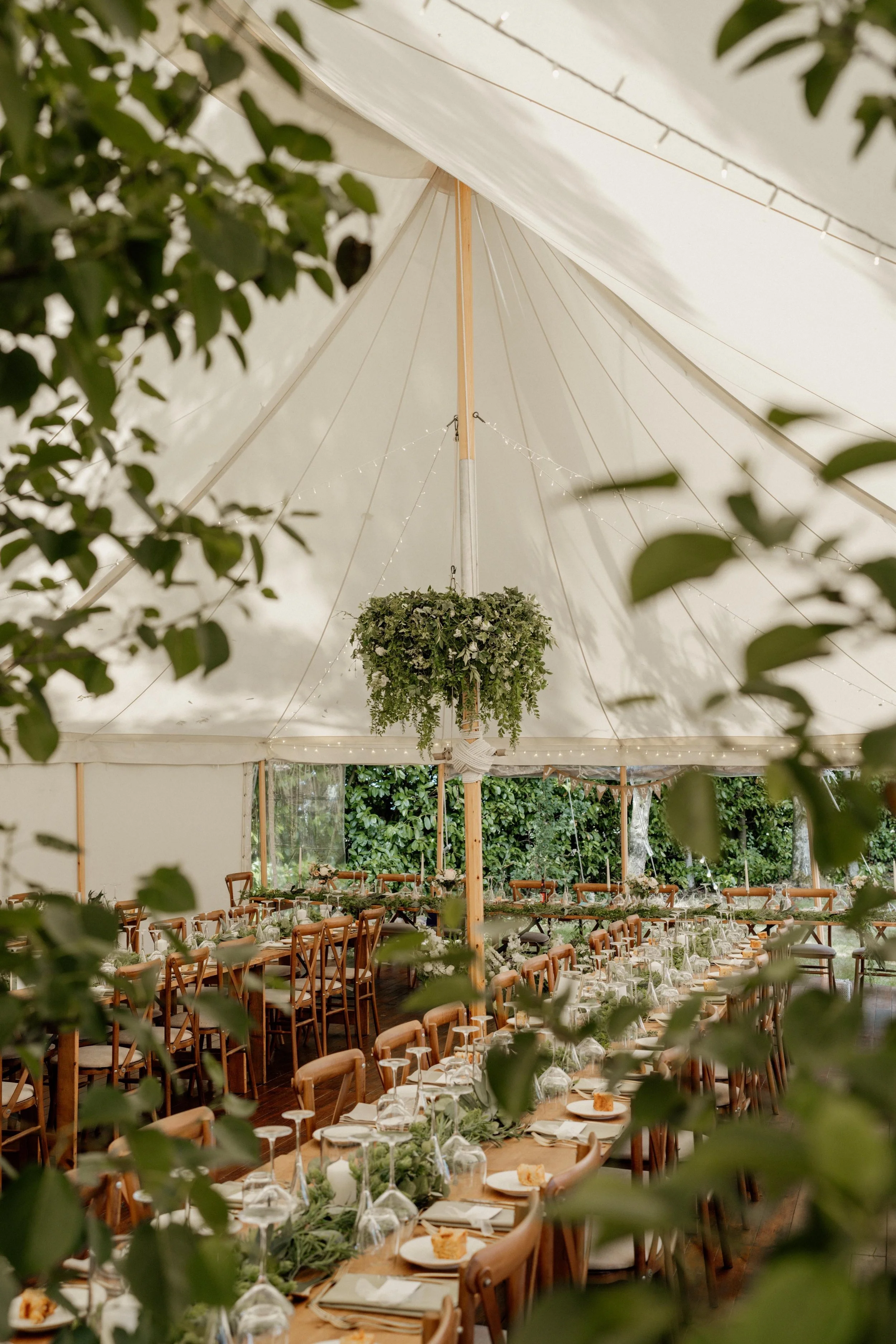 Marquee wedding reception styled with hanging greenery and artificial wedding flowers