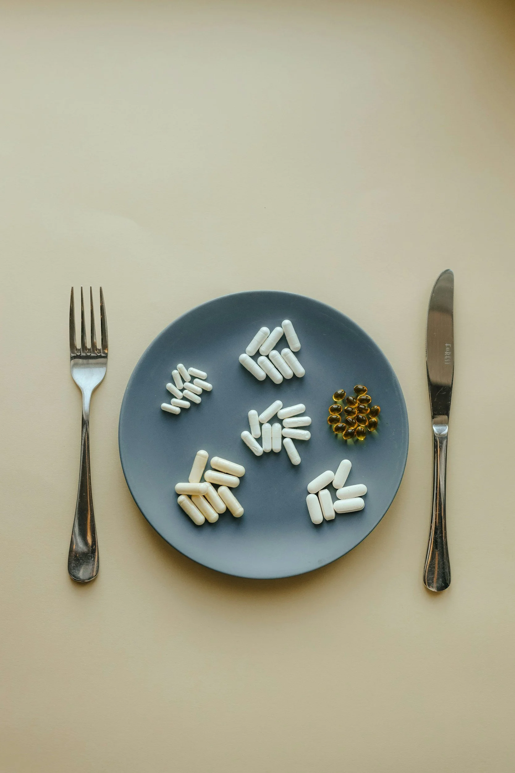 Fork and knife set outside a plate with multiple supplements laid out
