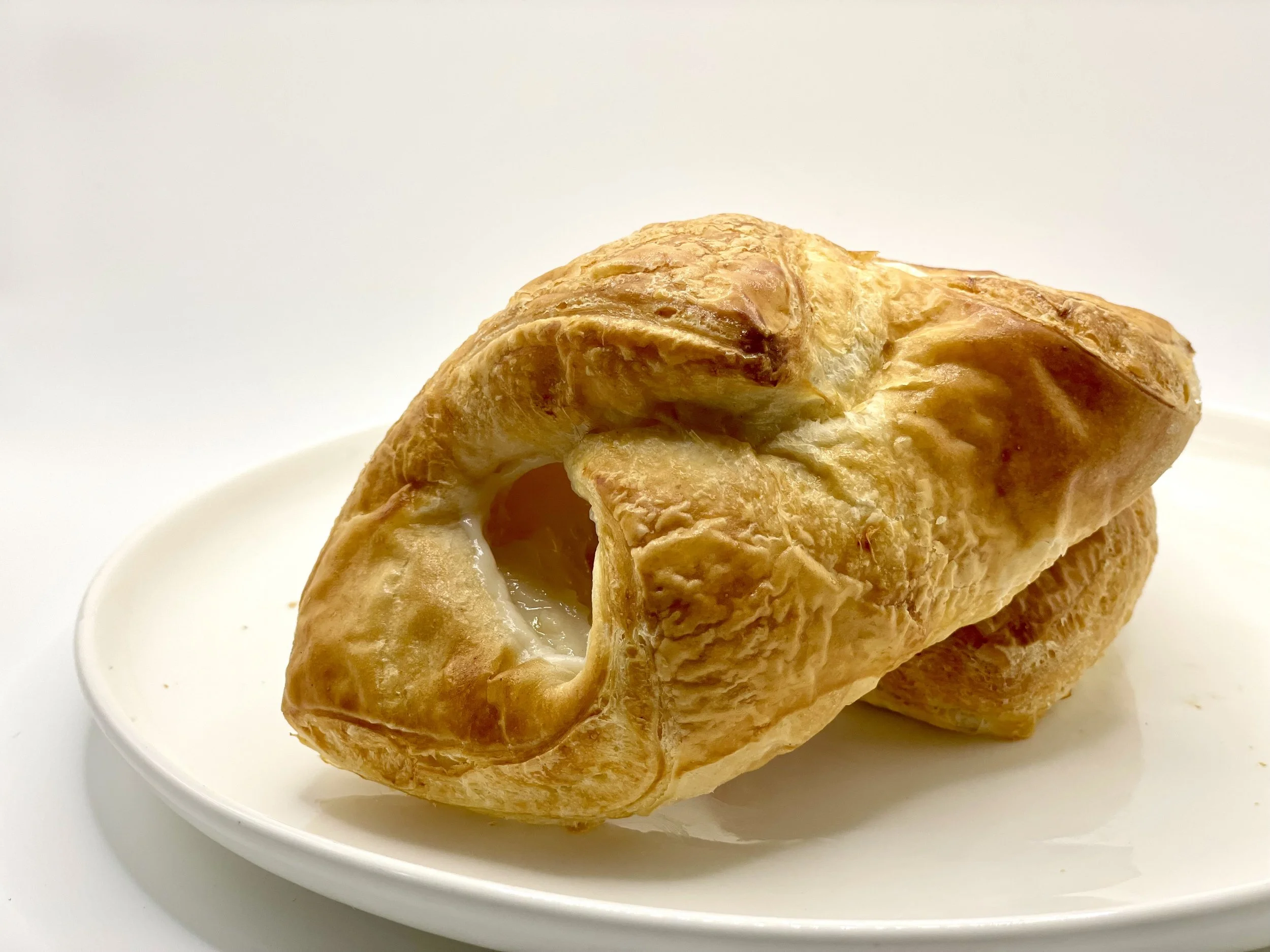 Close-up of a baked puff pastry with a golden-brown crust, served on a white plate.