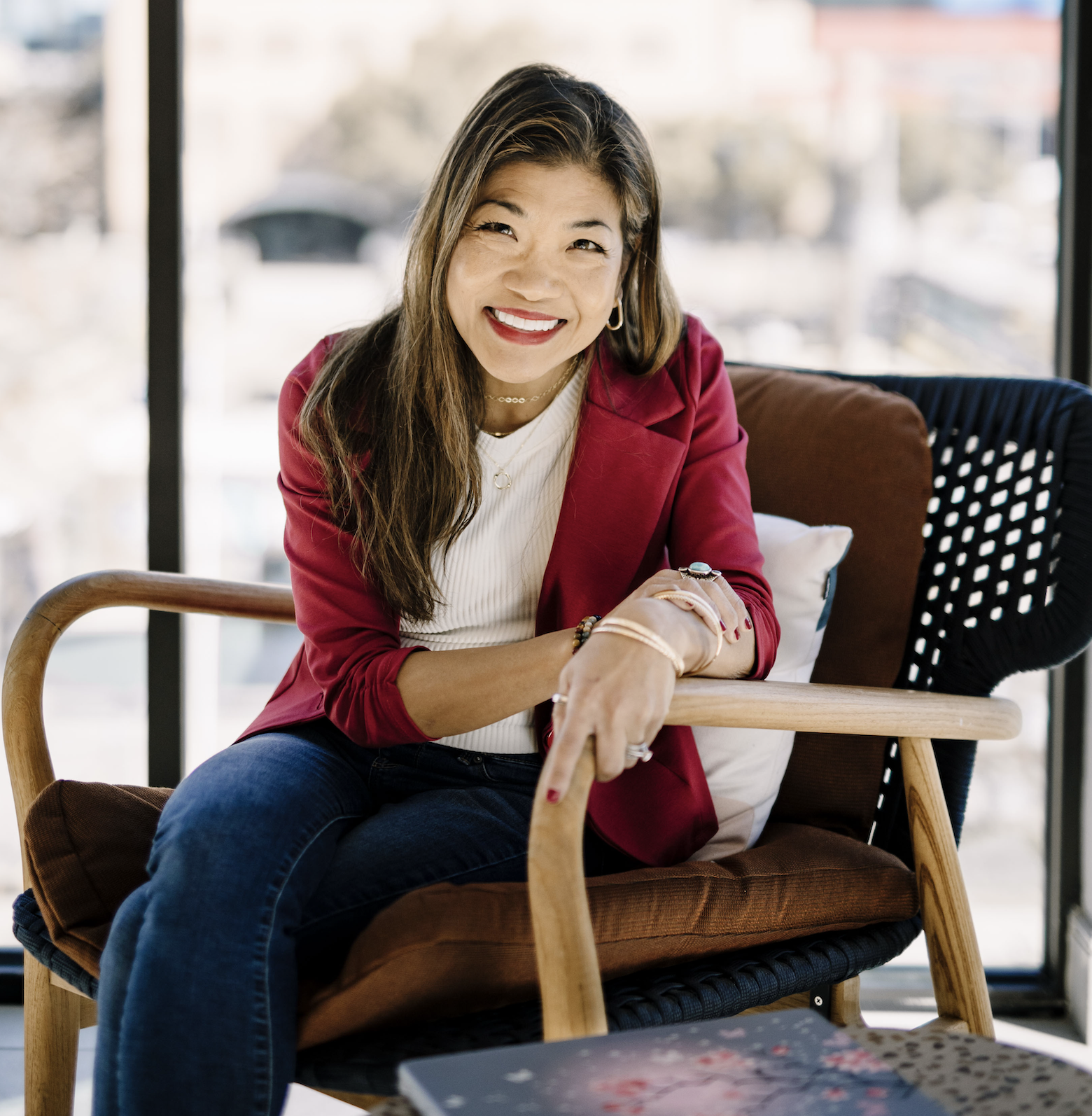 Dori Martin in red blazer sitting on chair smiling