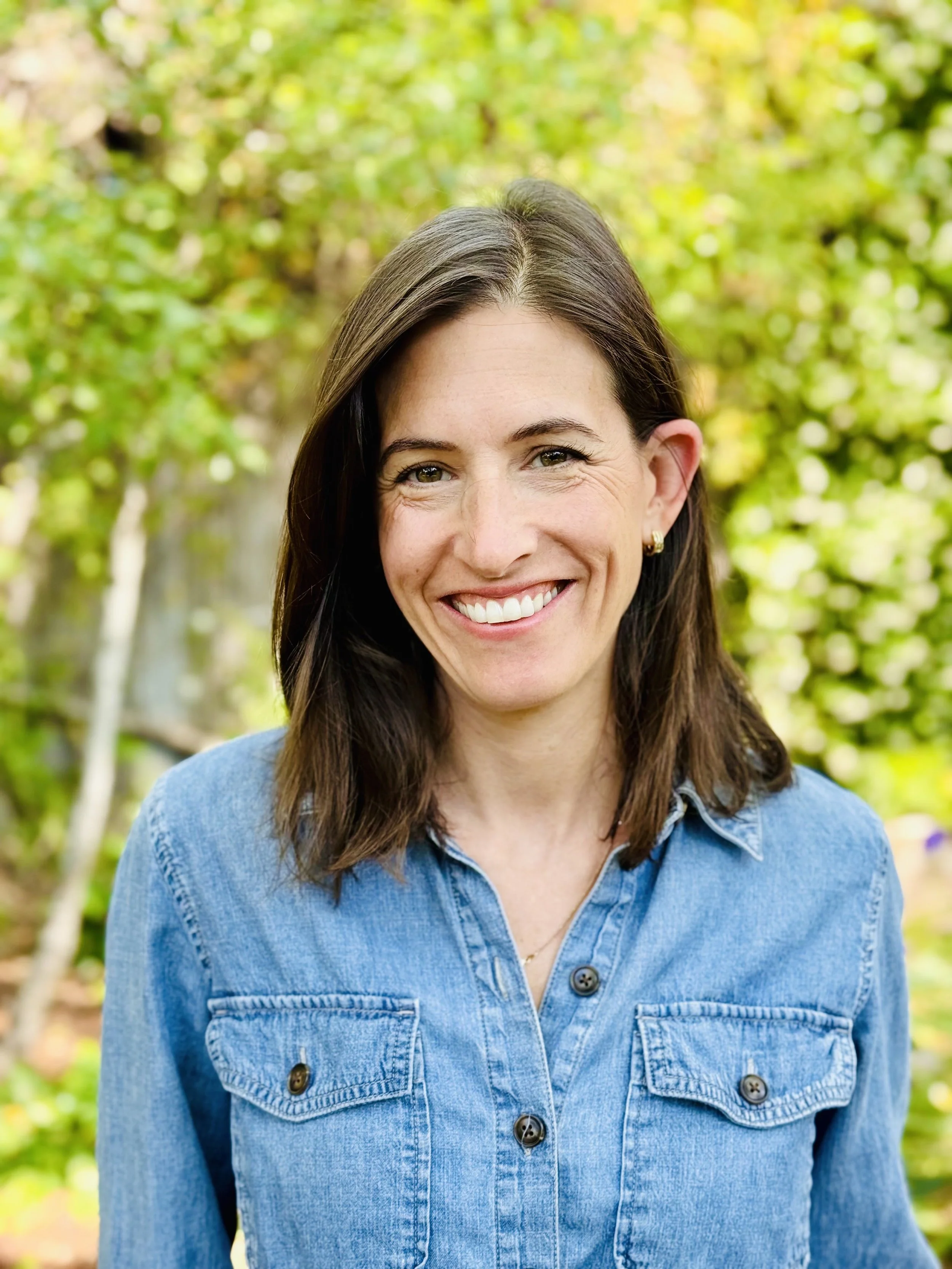 brunette woman in denim shirt smiling