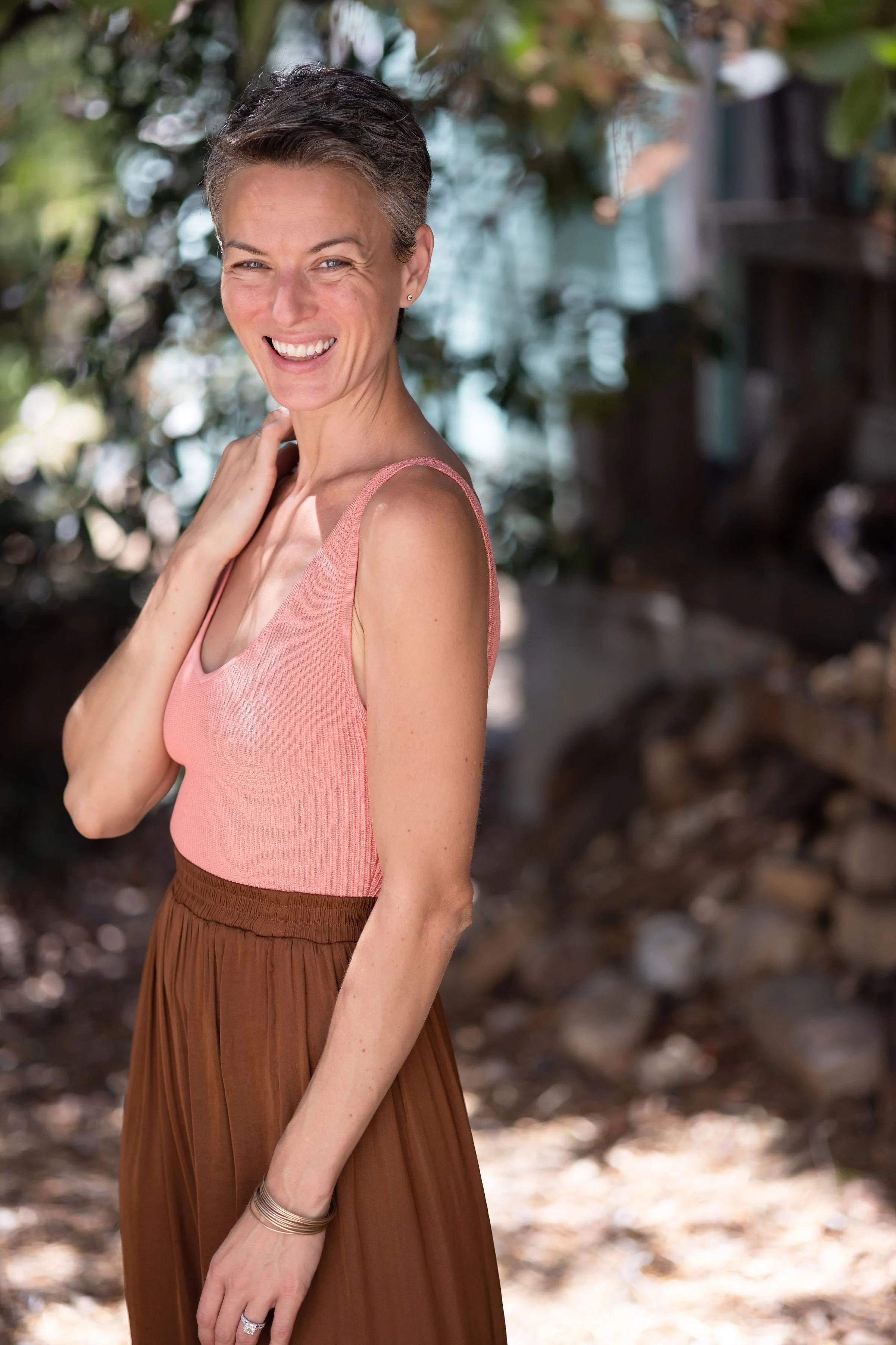 May Lindstrom in pink tank and brown pants smiling at camera