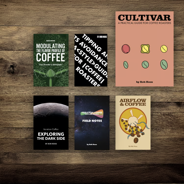 Rob Hoos has written a number of books about coffee roasting. This is a picture of those book on a wooden table.