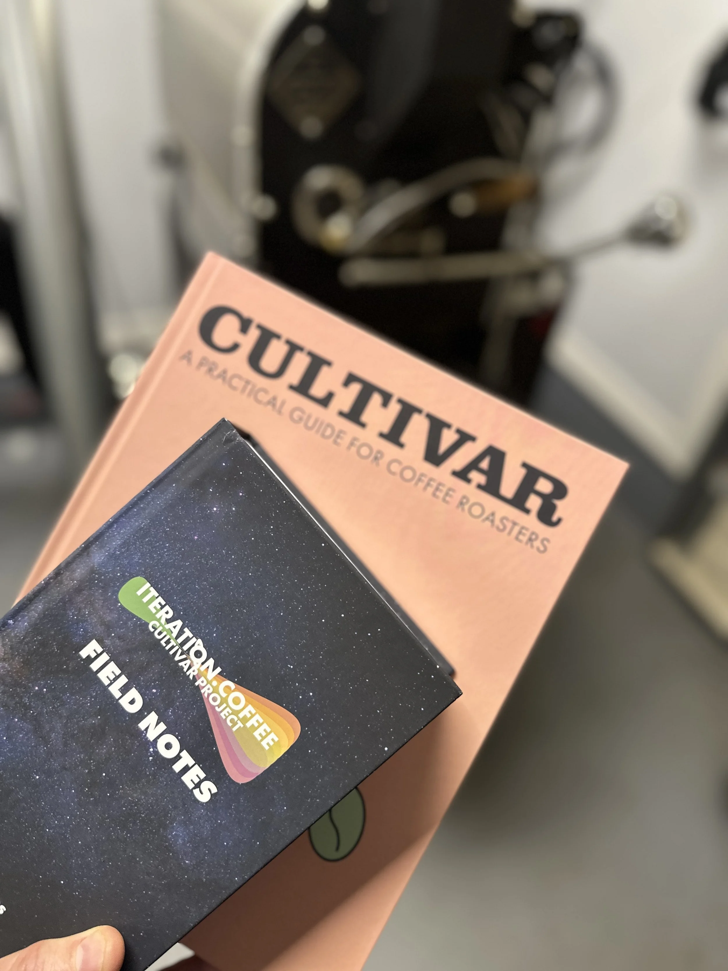 This is a picture of Rob's books cultivar and field notes in front of a traditional drum roaster. Rob Hoos uses these books to teach how to roast coffee.