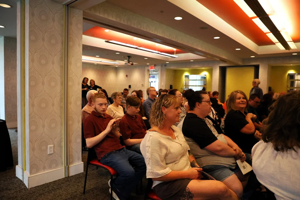  Audience at event sitting in chairs.  
