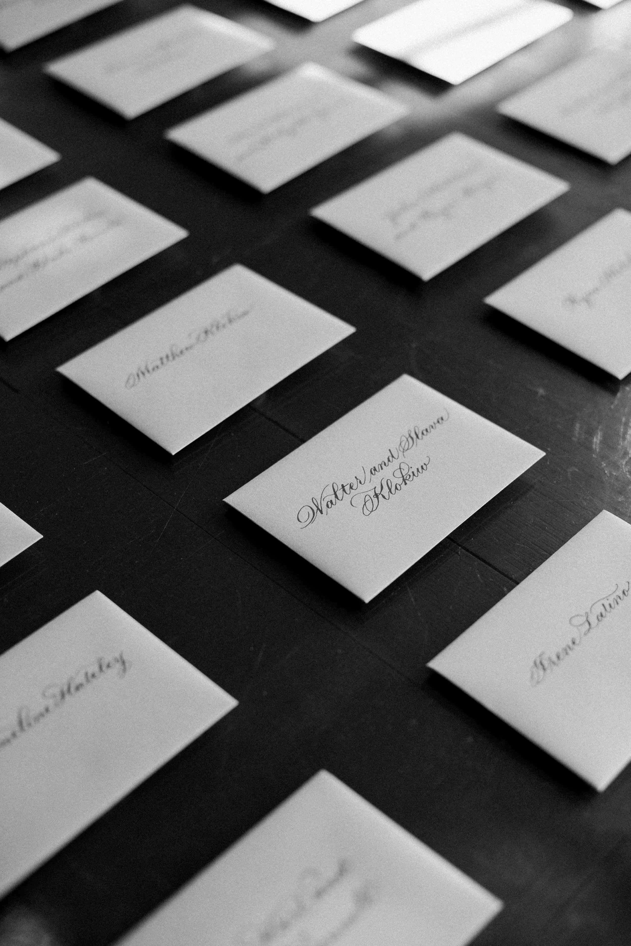 Name cards with elegant cursive text on a black surface arranged in a grid pattern.